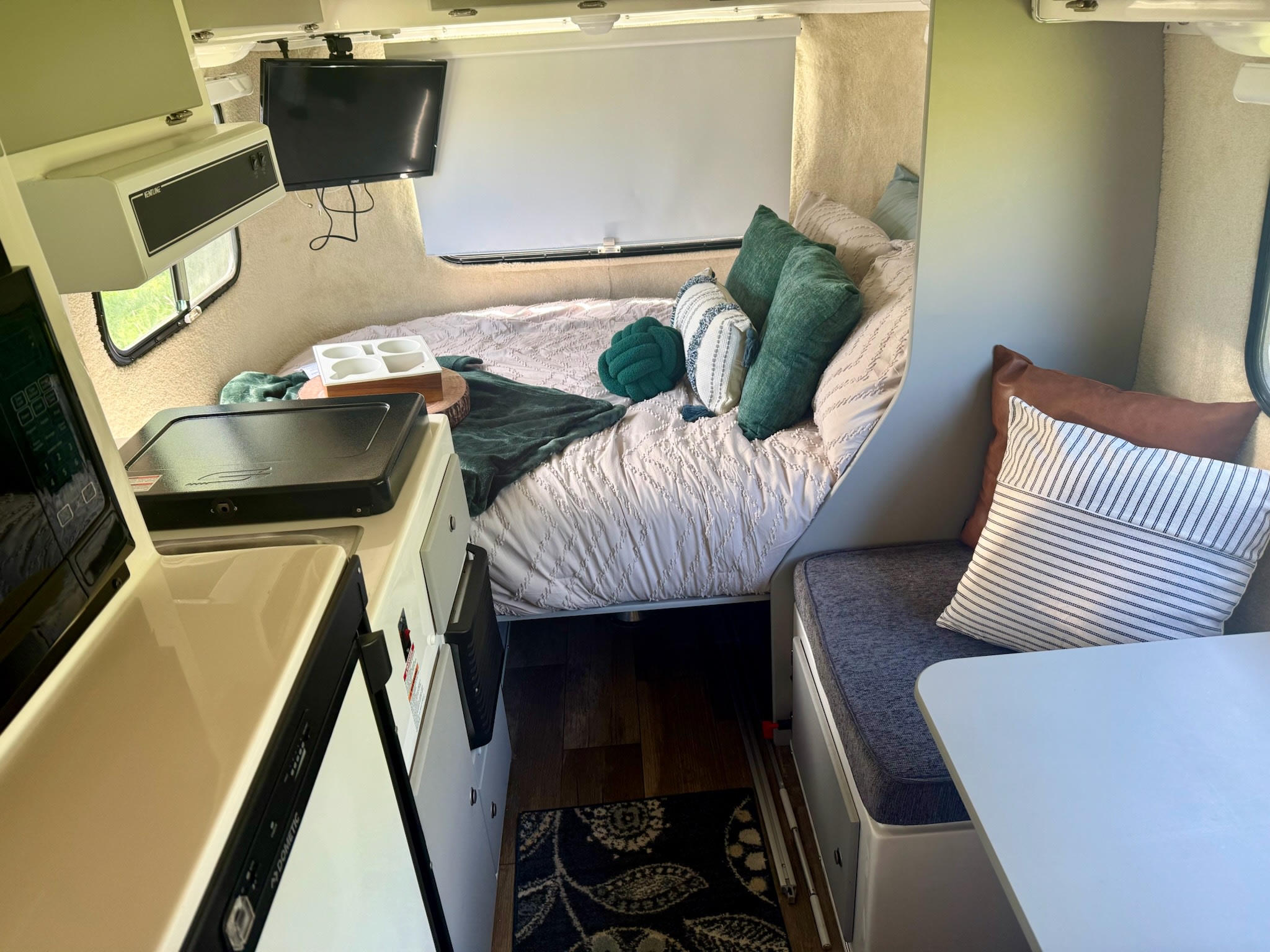 Cozy rv rental interior featuring a bed with pillows, compact kitchen area, and a dining nook with a table.. Casita Casita Trailer 2022