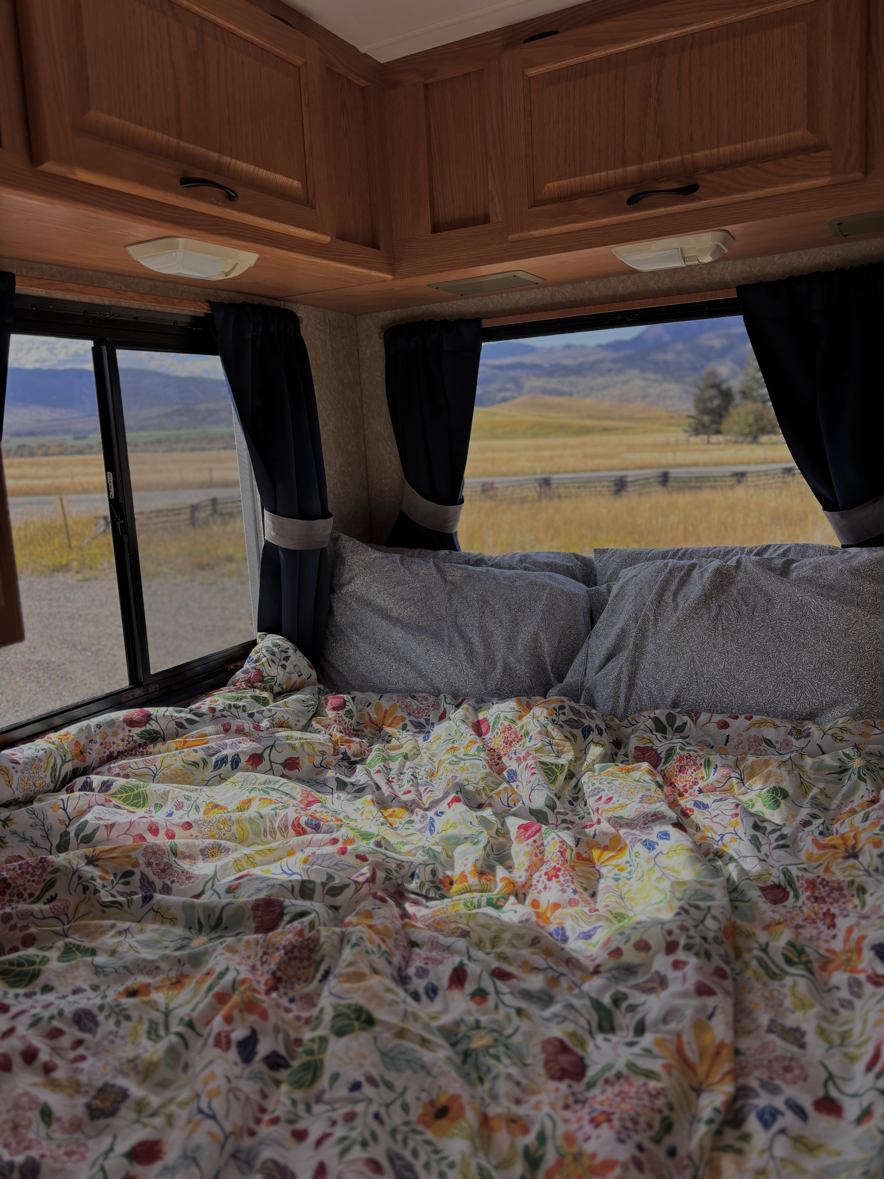 Relax in your rv rental's cozy bed with a colorful floral duvet and a beautiful view of nature outside.. Four Winds Majestic 2006