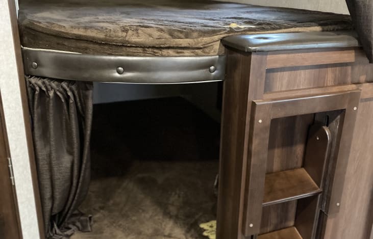 Cozy rv rental bunk bed with brown mattress, privacy curtain, and integrated wooden ladder for easy access.. Jayco Jay Flight SLX 2019