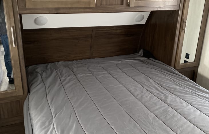 Cozy RV rental bedroom featuring a comfortable bed, overhead storage, and built-in reading lights for a relaxing trip.. Forest River Cherokee Grey Wolf 2019