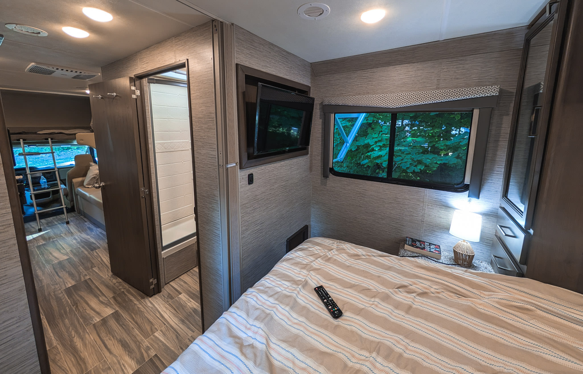 Experience the comfort of this modern RV rental's bedroom, living area, and full bathroom, ideal for adventurous travel.. Thor Four Winds 2021