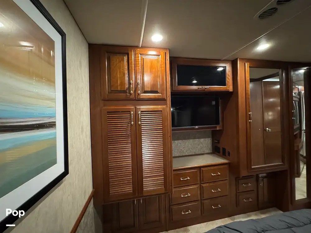 Comfortable RV rental bedroom featuring rich wood cabinetry, two TVs, and a large mirror. Ideal for your next road trip.. Fleetwood Southwind 34A 2016