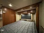 Cozy RV rental bedroom with a large bed, warm wood paneling, and bright overhead lighting, ideal for your next trip.. Fleetwood Southwind 34A 2016