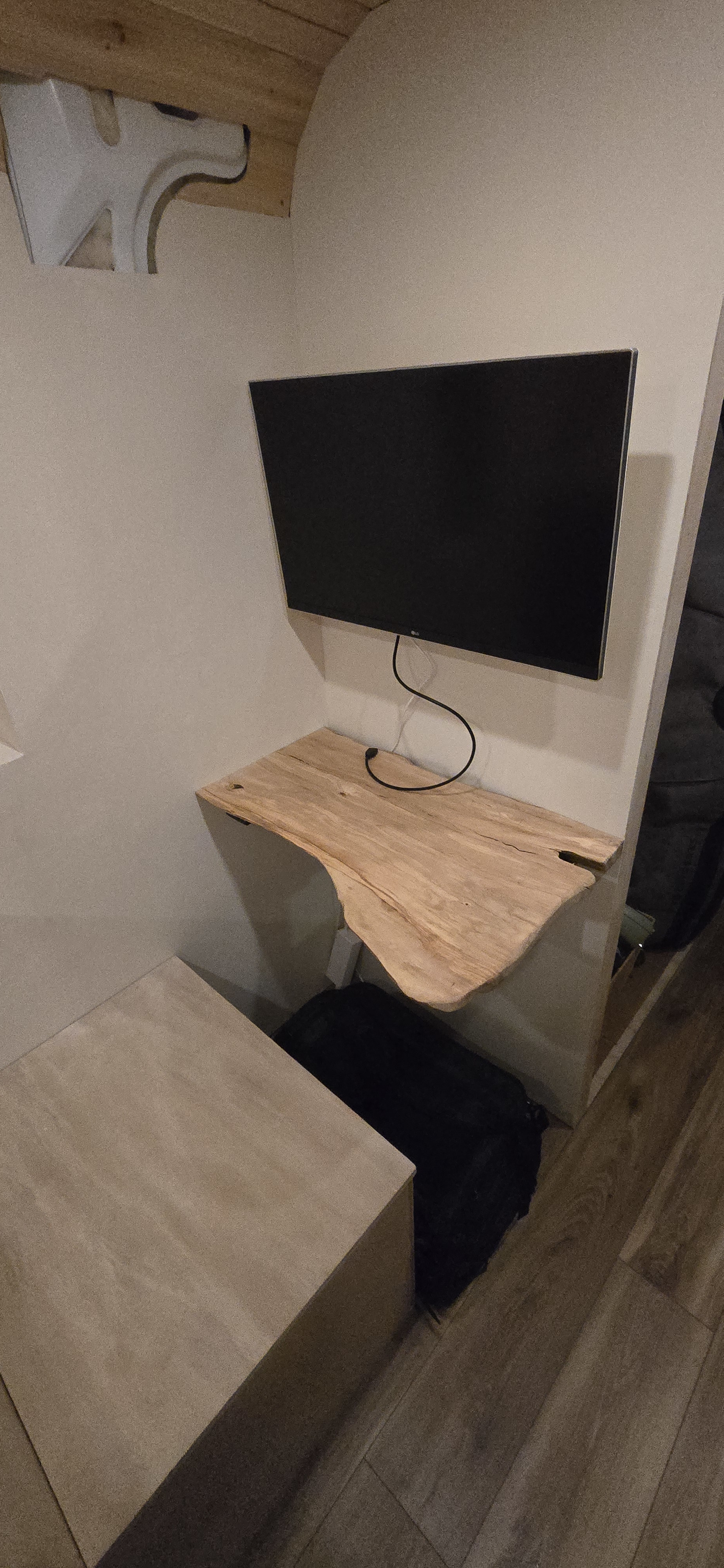 RV rental interior features a wall-mounted TV above a live-edge wooden shelf, with a light-colored cabinet nearby.. Dodge 1500 2023