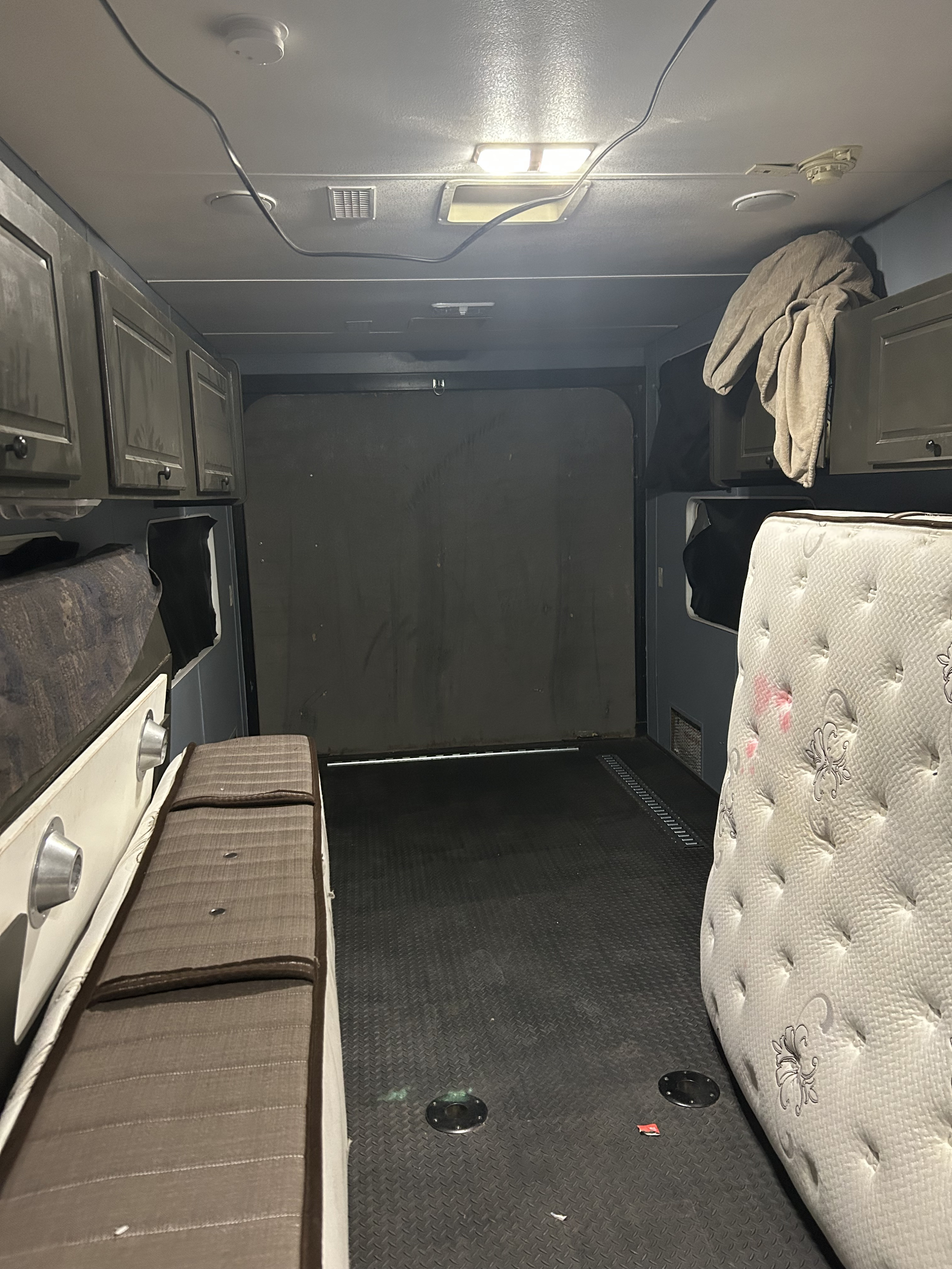 Interior of an RV rental showing beds, overhead cabinets, and a textured floor, ready for travel or use.. Weekend Warrior 3705 2004
