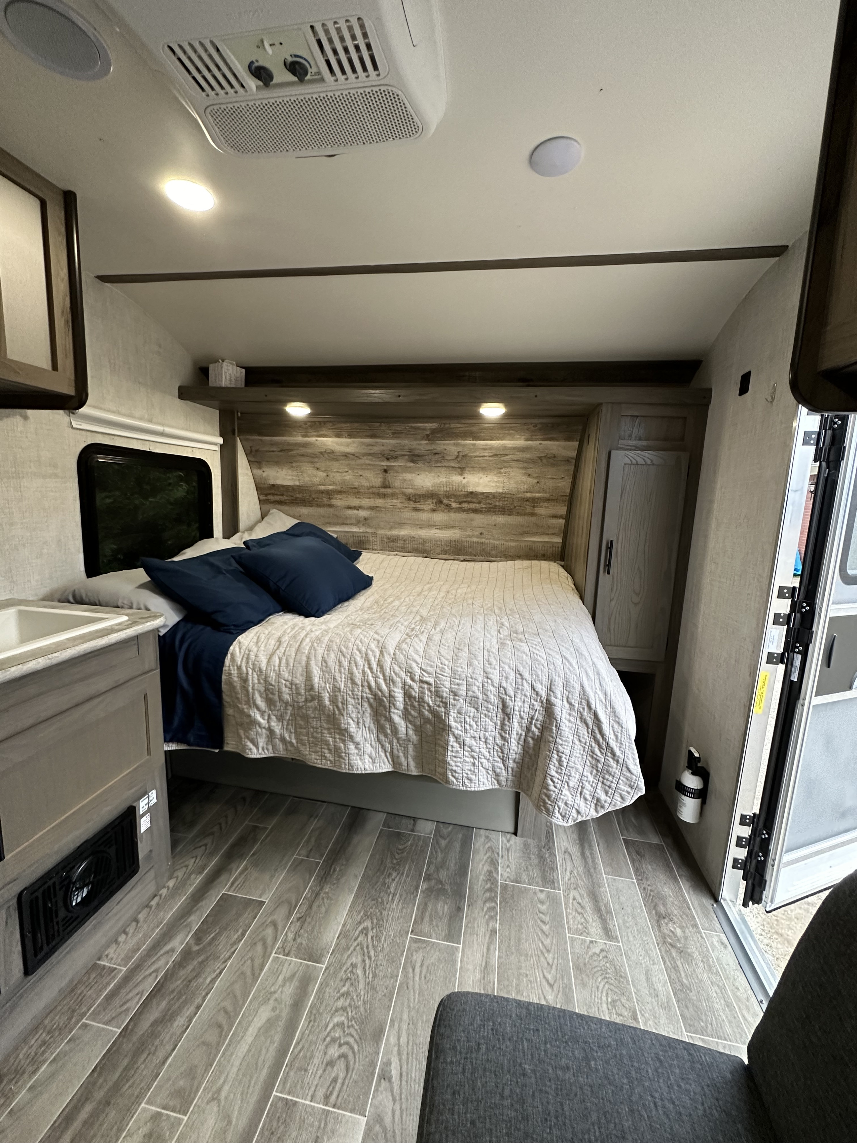 An inviting rv rental bedroom with a comfy bed, recessed lighting, wood-look headboard, and plank flooring. Your mobile retreat.. Gulf Stream Ameri-Lite 2021