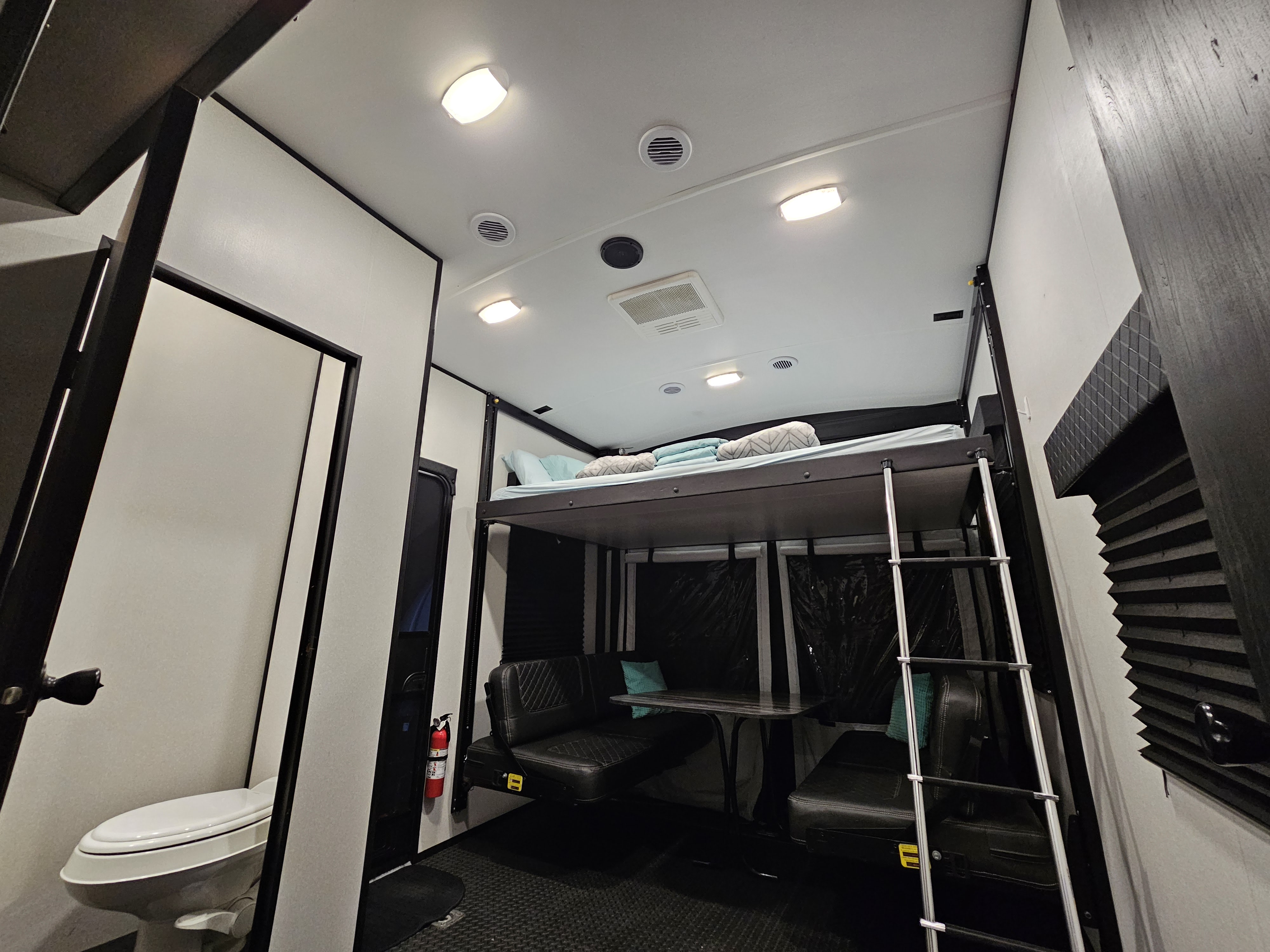 Inside this RV rental: a bunk bed with ladder, convertible dining benches, a toilet, and essential safety equipment visible.. Heartland RVs Torque Toy Hauler 2021