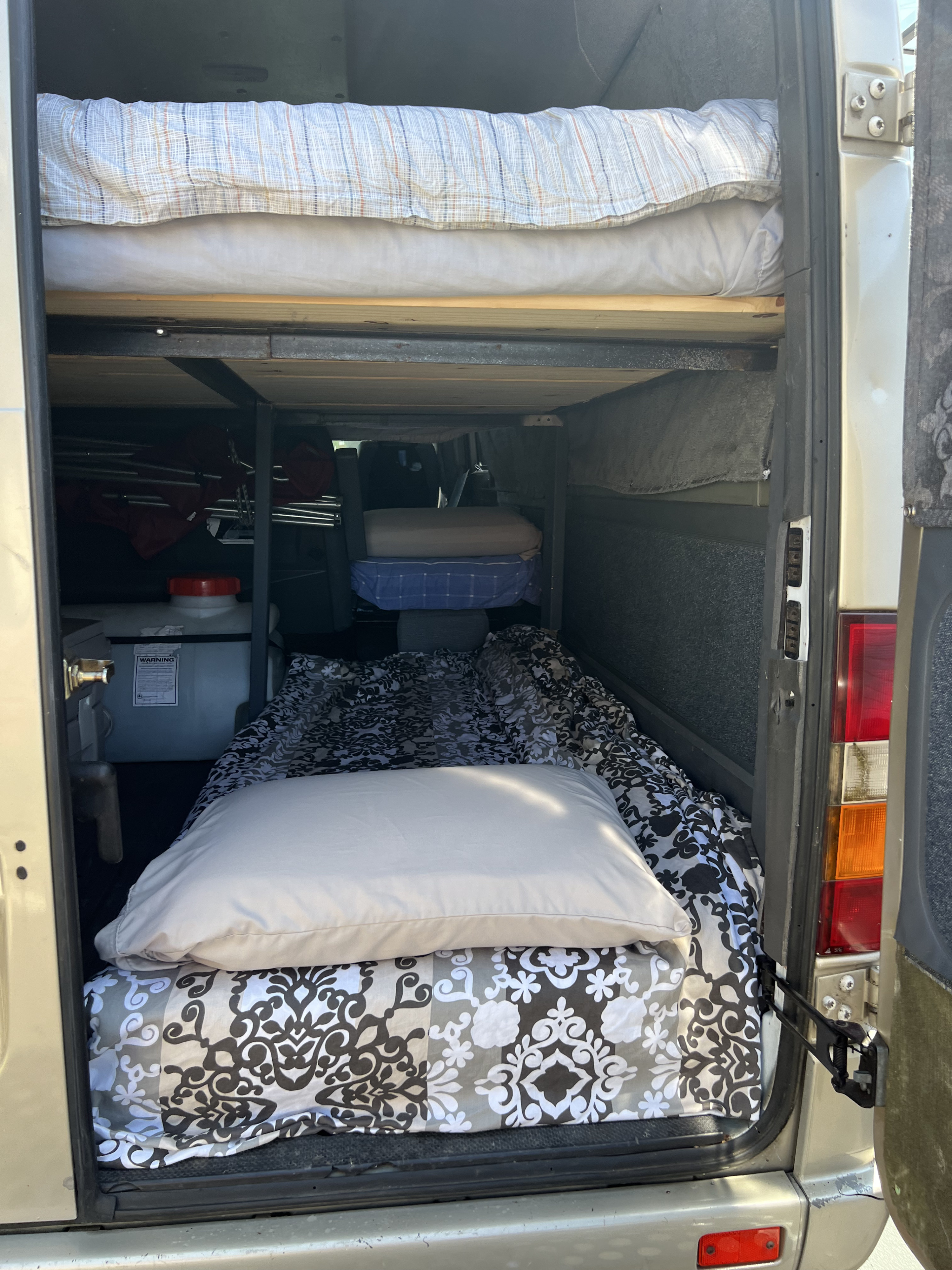RV rental: Camper van interior featuring practical bunk beds, a water tank, and storage area for travel essentials.. Mercedes-Benz Sprinter 2006