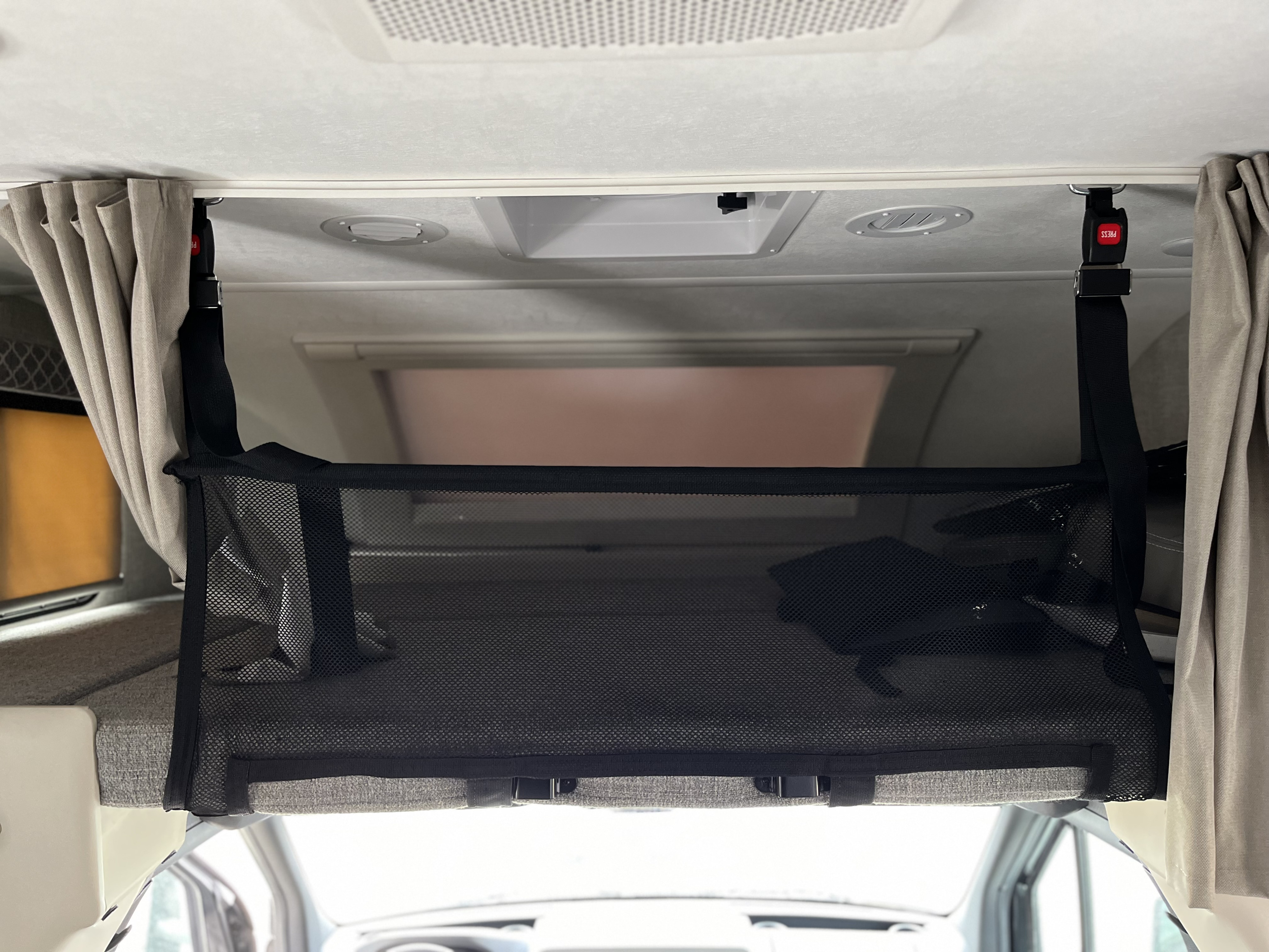 This RV rental features a black mesh storage net for overhead organization, secured with red-buckle straps in the cab-over area.. Thor Quantum 2022