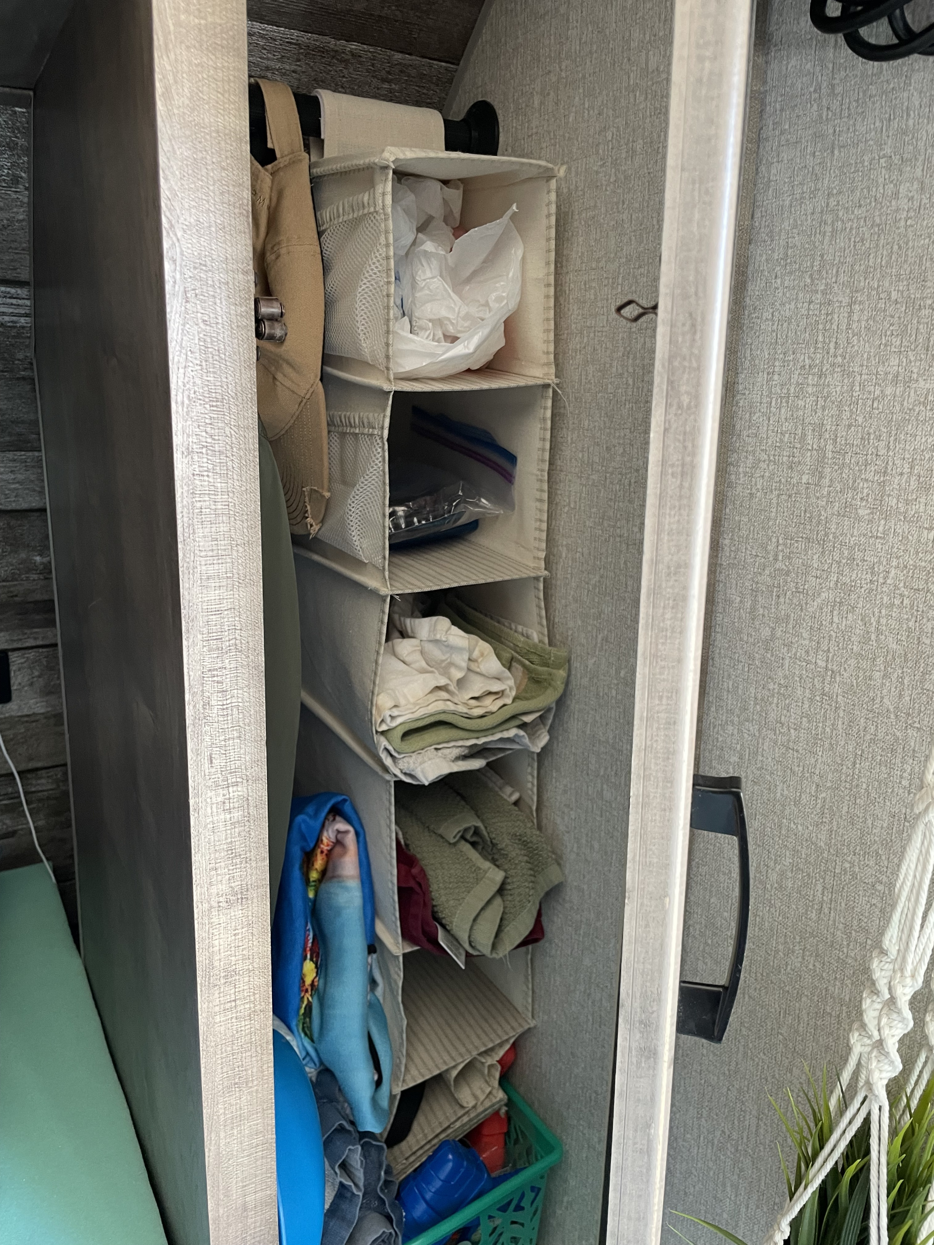 Inside an RV rental closet, a fabric hanging organizer stores folded towels, bags, and items. Efficient, compact storage solution.. Venture Sonic Lite VBH 169 2022