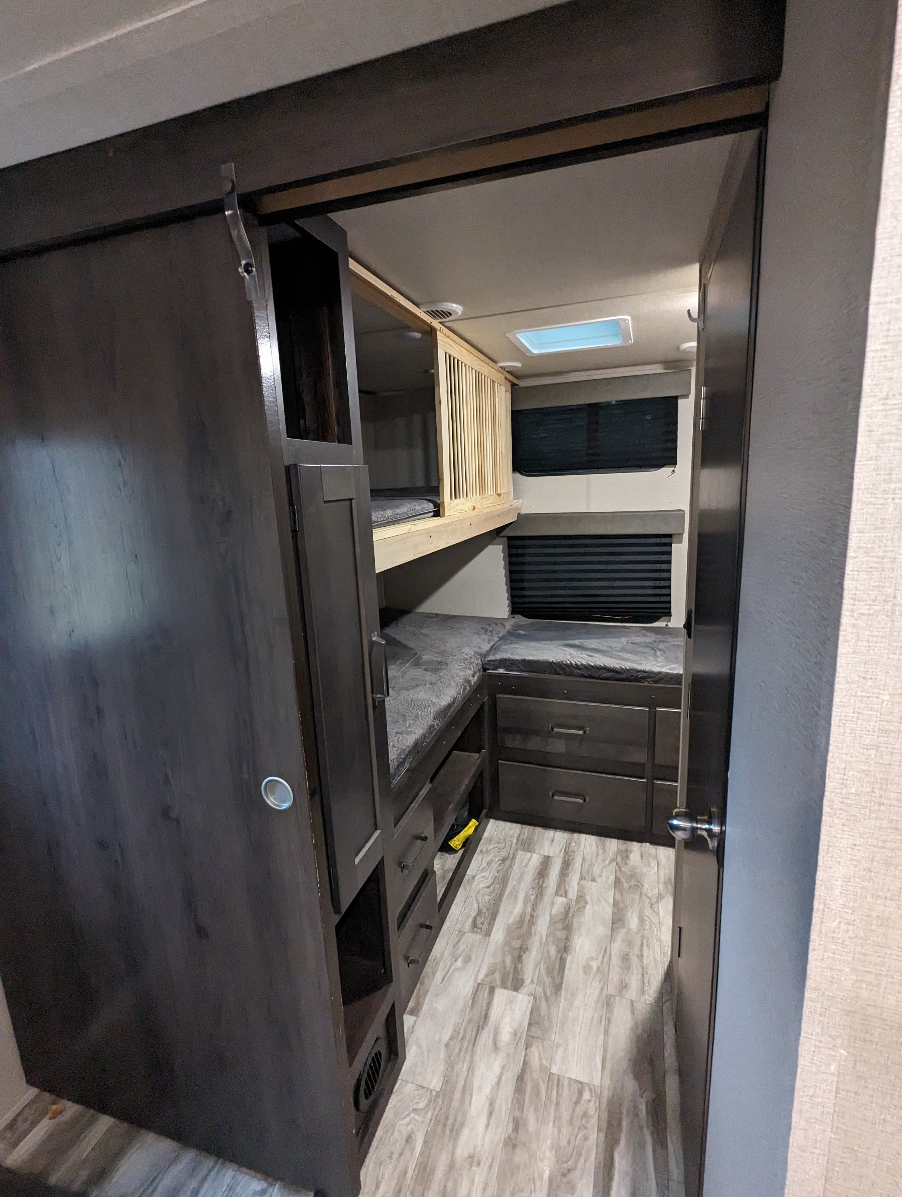 RV rental bunkhouse interior: features wooden bunk beds with railings, cushioned seating, storage drawers, and wood-look flooring.. Grand Design Transcend Xplor 2022