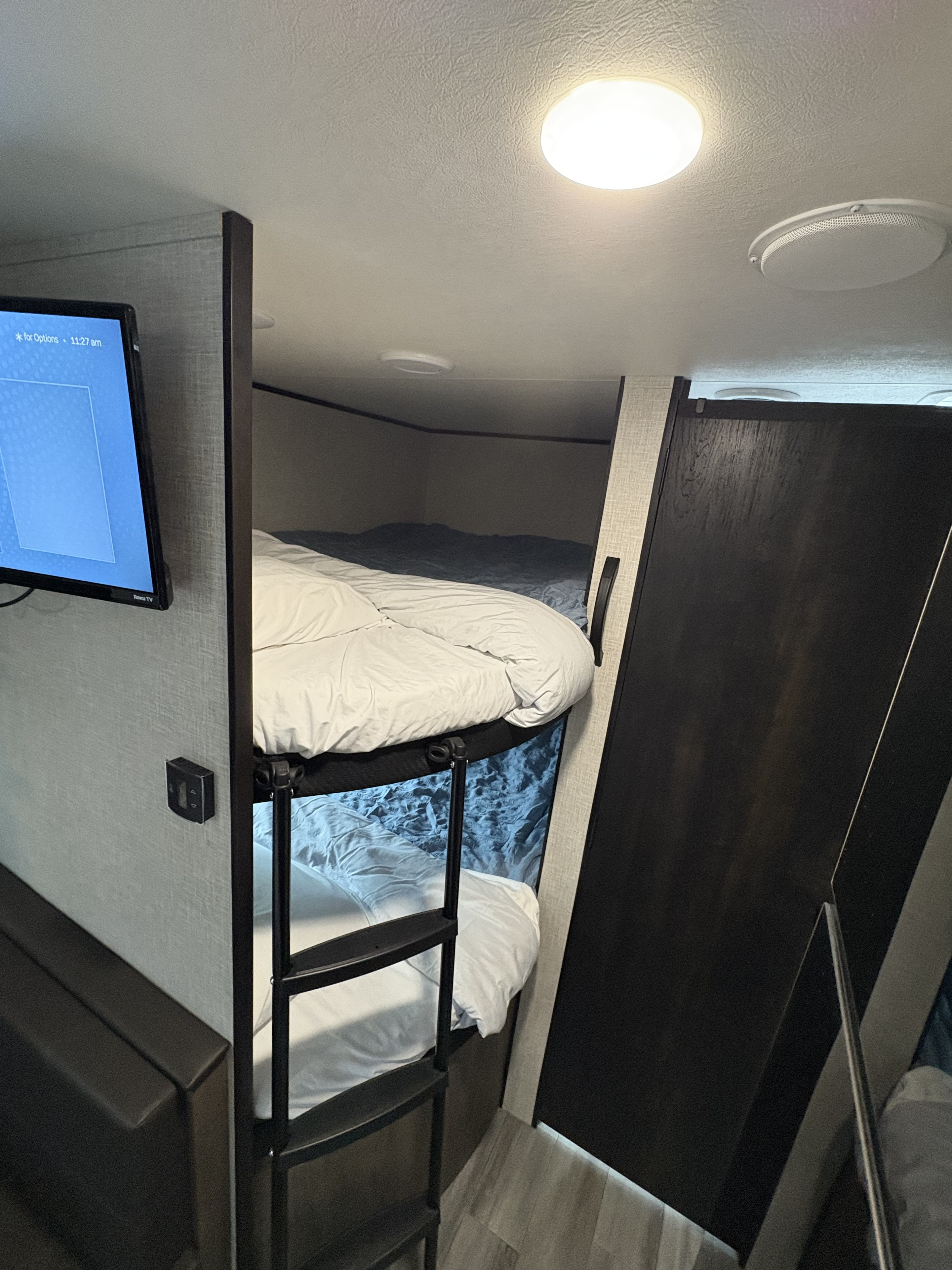 Comfortable RV rental interior with stacked bunk beds, a ladder, TV, and bright ceiling lights.. Jayco Jay Flight SLX 2024