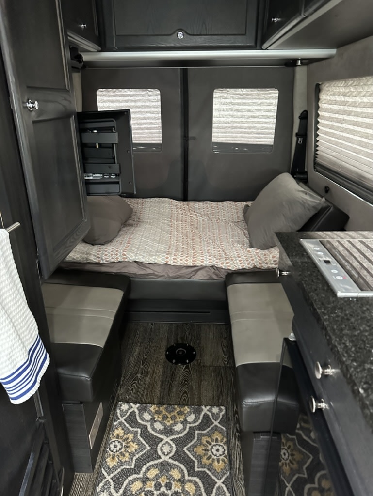 This rv rental features a cozy bed, dinette seating, and a compact kitchenette with a stovetop for comfort on the road.. Roadtrek SS AGILE 2017