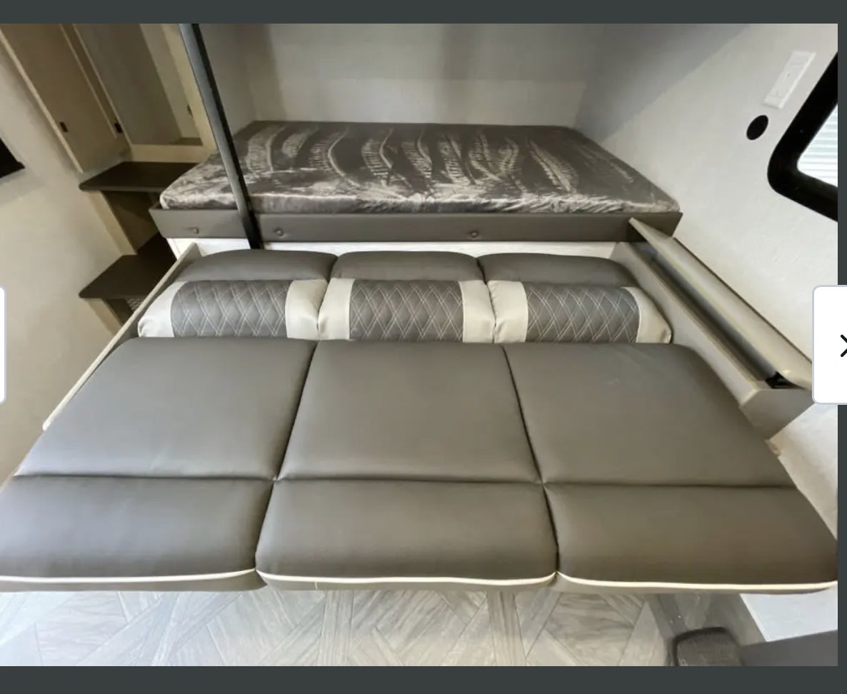 Modern RV rental interior with bunk beds, a convertible sofa, and sleek storage. Perfect for camper adventures.. Forest River Wildwood 2024