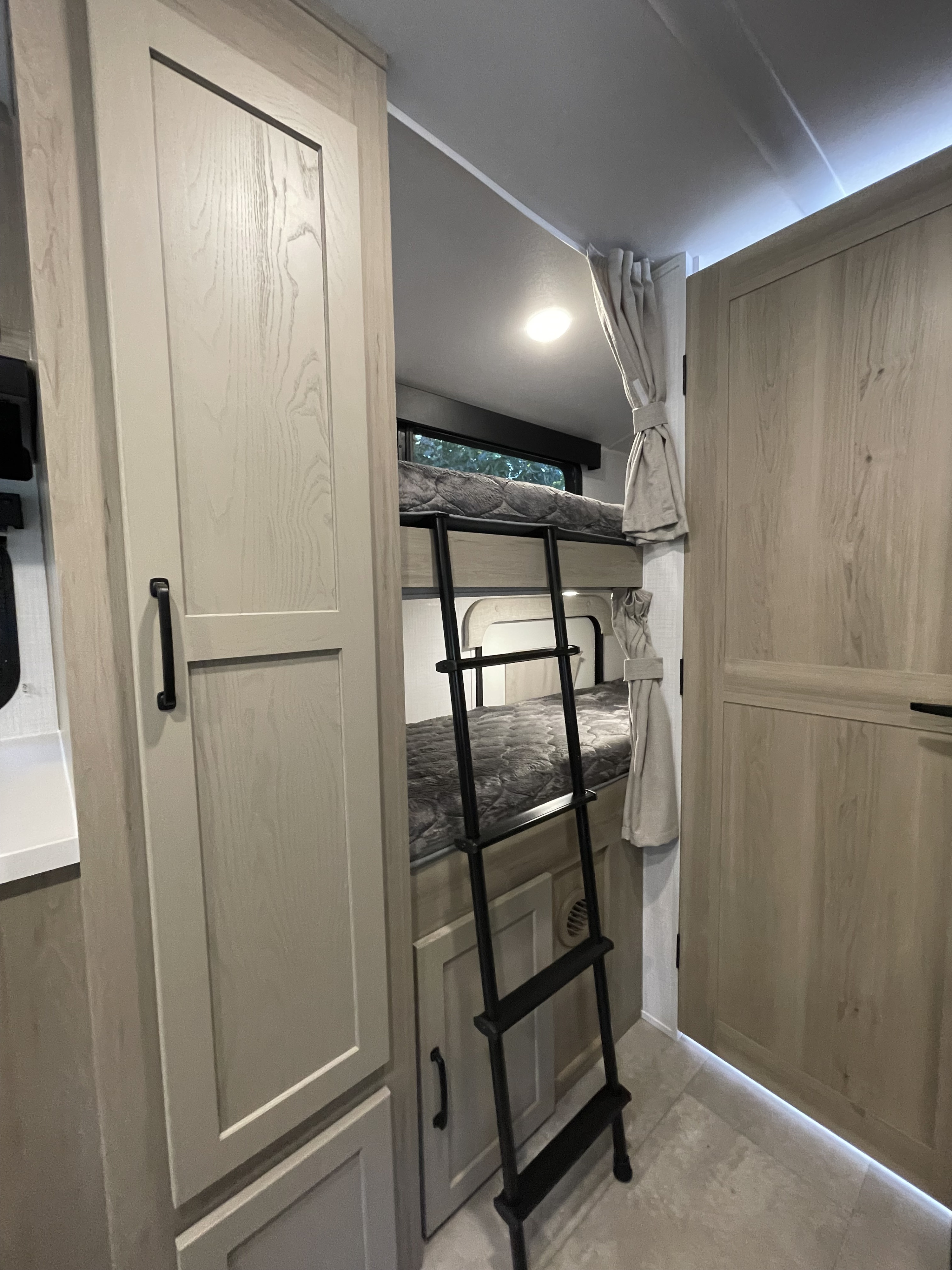 Cozy RV rental interior: bunk beds with ladder, light wood cabinetry, and ambient lighting for comfortable travel.. Forest River Rockwood Geo Pro 2025