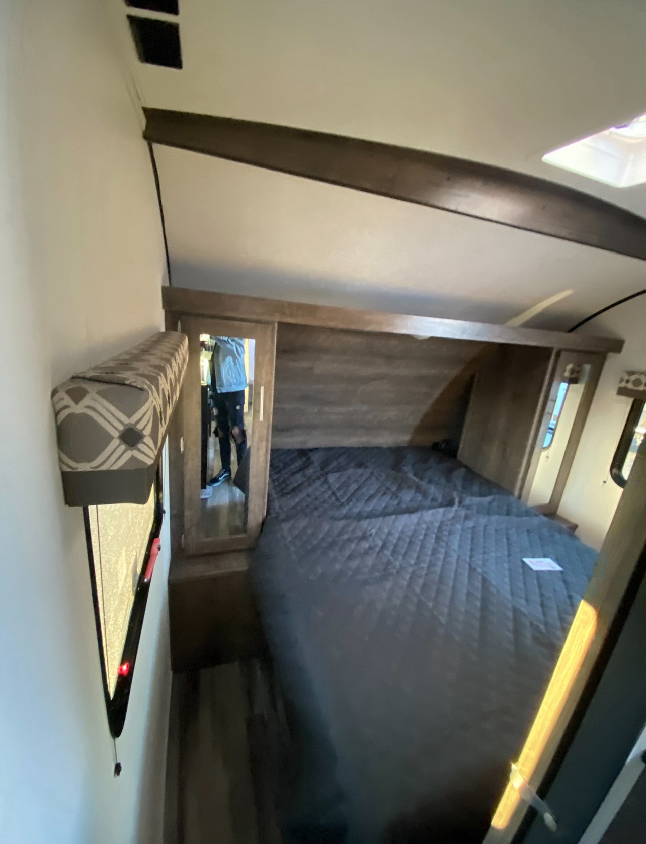 Cozy RV rental bedroom with a dark quilted bed, mirrored closets, and window for a comfortable journey.. Riverside RV Intrepid 2022