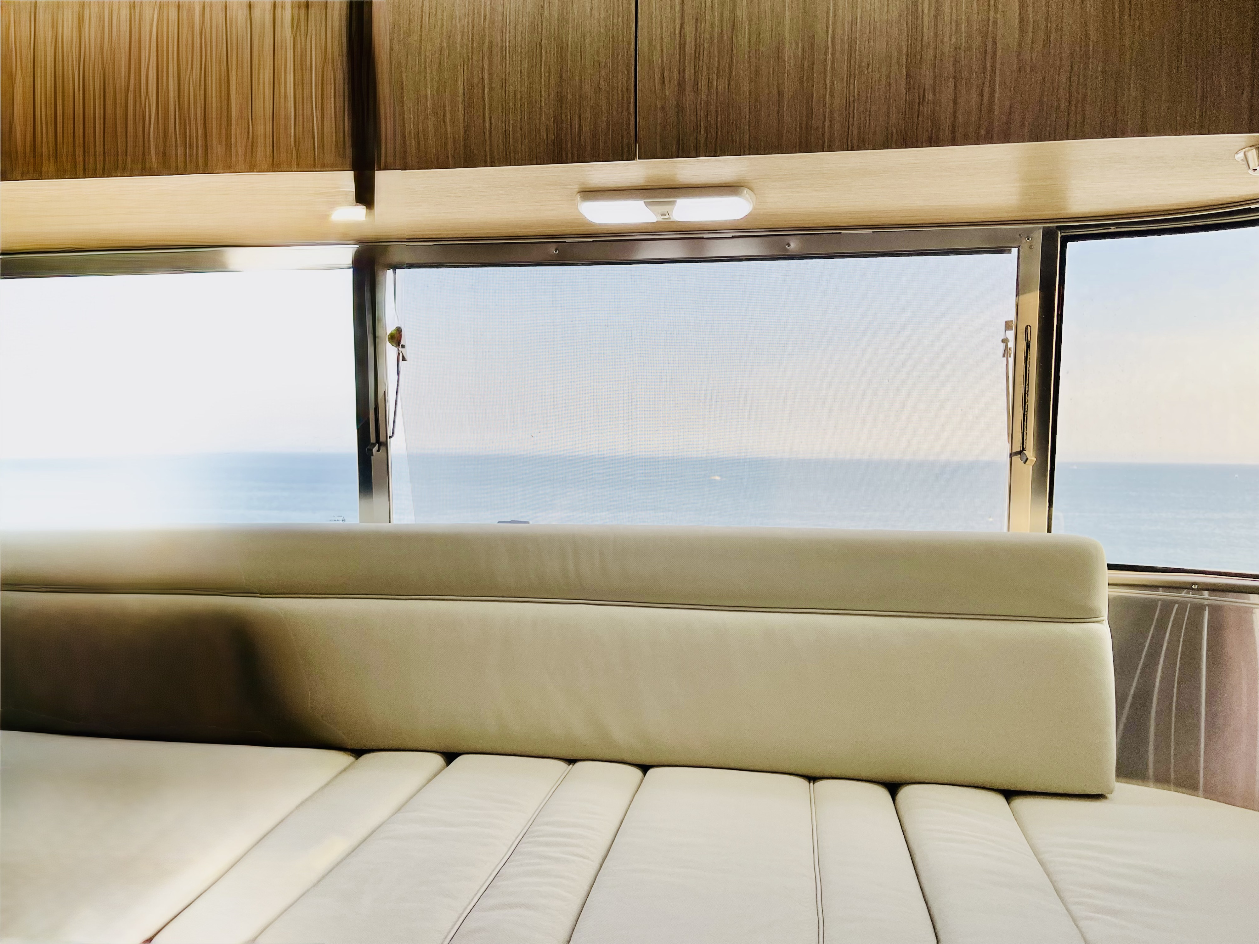 Enjoy the serene ocean view from the comfortable bench seating inside this RV rental. Perfect for travel relaxation.. Airstream Flying Cloud 2017