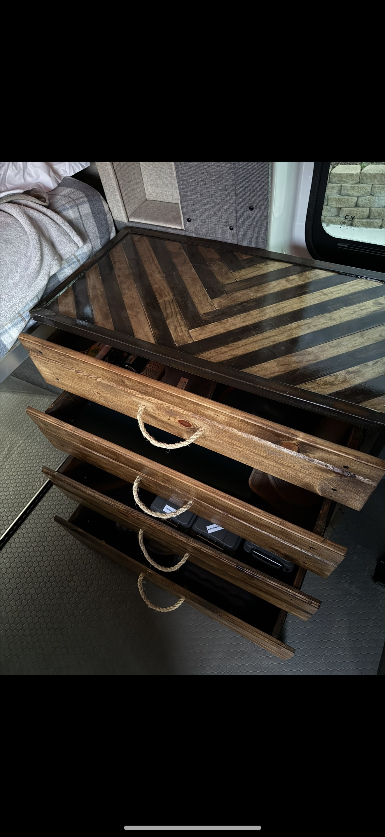 Custom RV rental interior: herringbone countertop & rustic wooden drawers with rope handles. Cozy van storage.. Ford T-250 AWD 2022