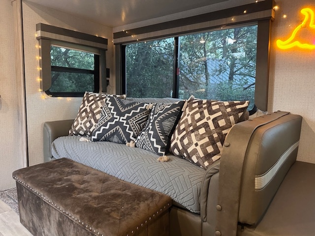 Enjoy this RV rental's cozy interior: a sofa with patterned pillows, storage ottoman, string lights, and nature views.. Winnebago Minnie 2022
