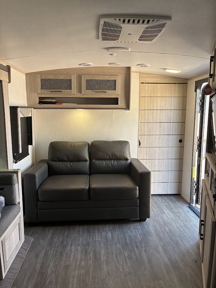 This RV rental features a comfortable gray sofa, modern overhead cabinets, and durable wood-look flooring.. Twilight RVS Signature 2022