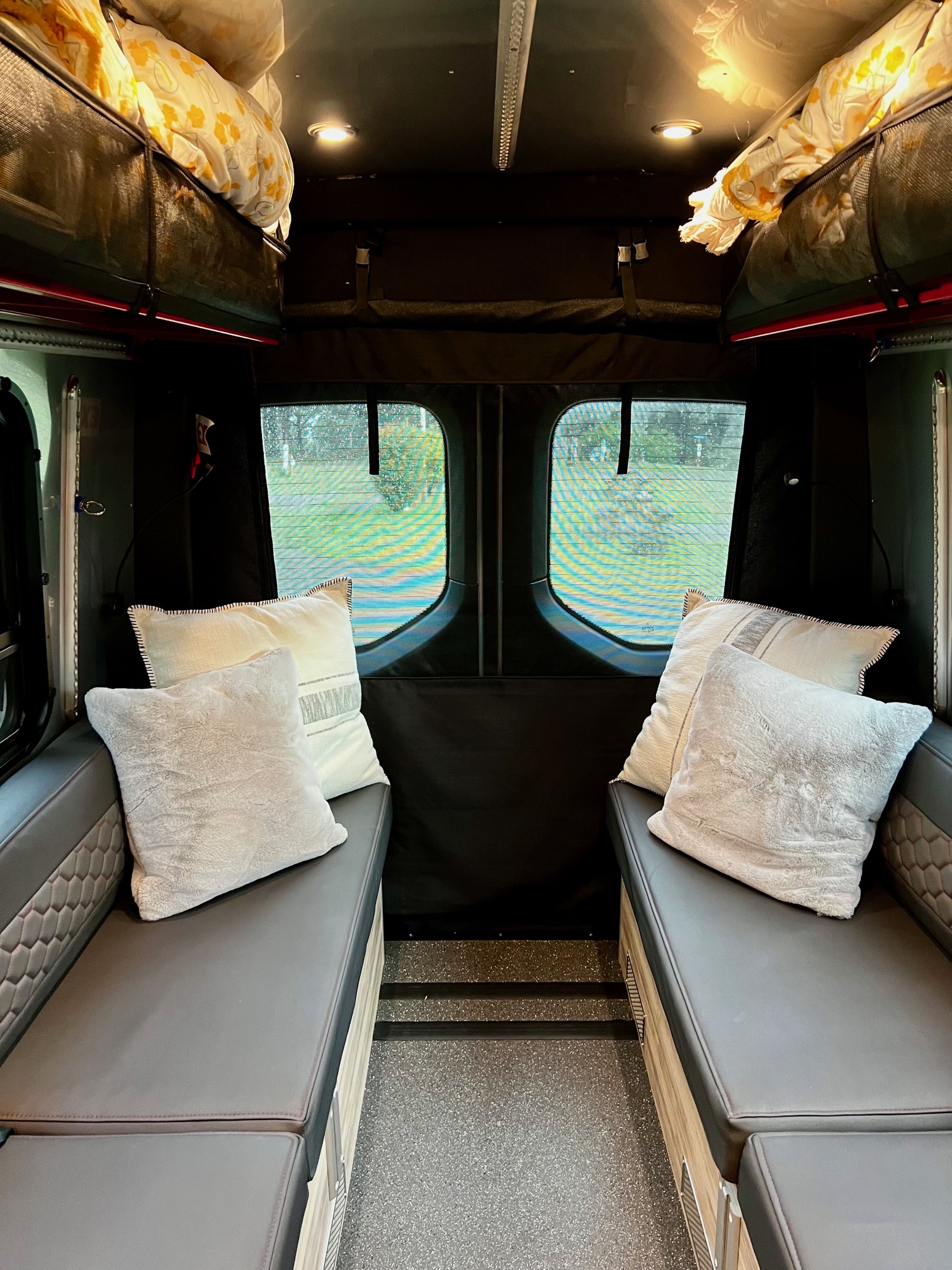 Inviting rv rental interior: dual benches with pillows, overhead storage, and screened windows for scenic views.. Airstream Interstate 2022