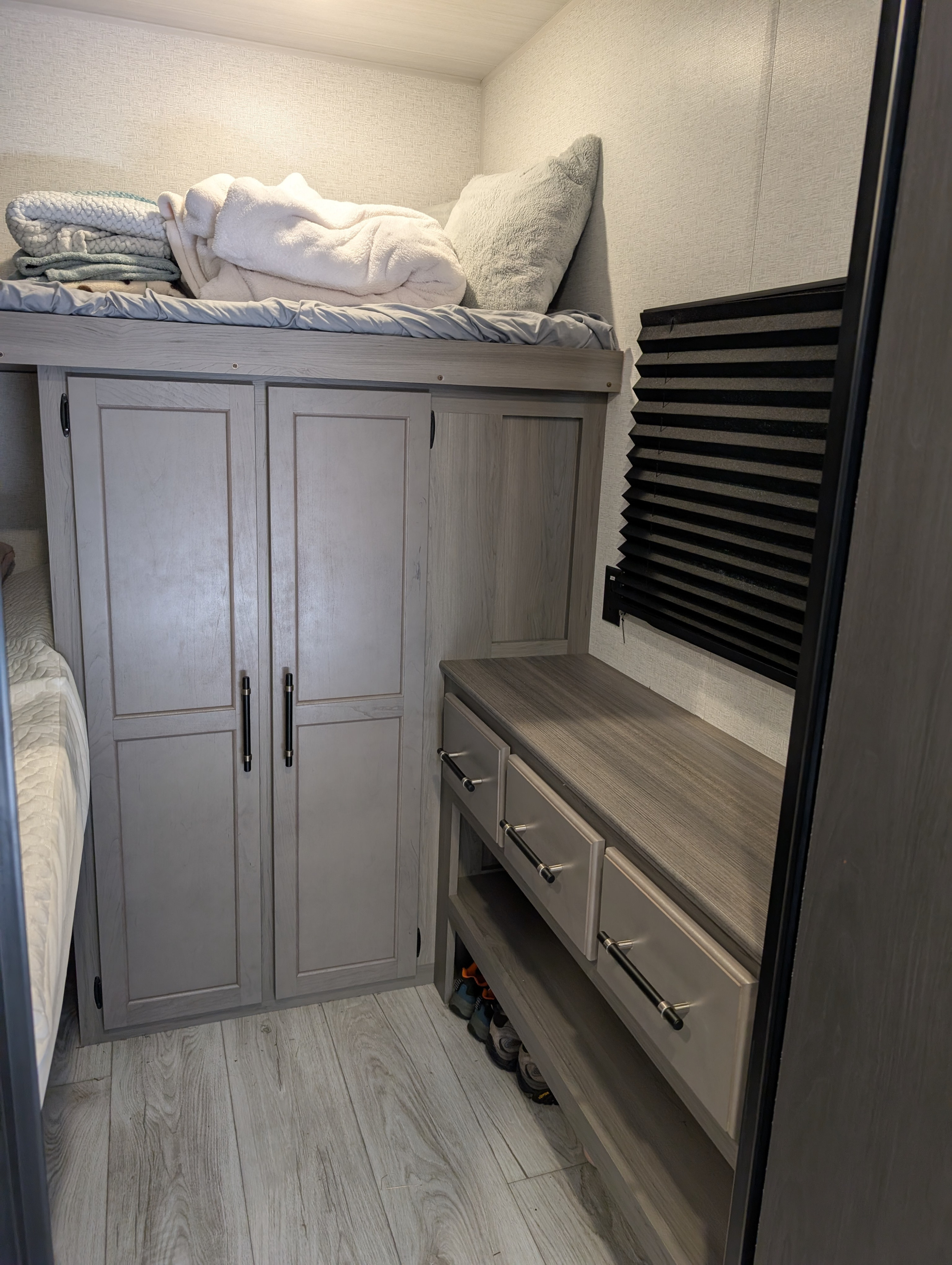 RV rental: bunk bed, light wood wardrobe, and dresser with open shelving for shoes. Modern interior design.. Keystone RV Hideout 2025