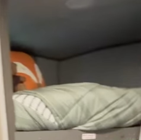 RV rental bunk bed with an orange pillow and a light green striped comforter, offering a cozy, compact sleeping space.. Cruiser RV Shadow Cruiser 2020