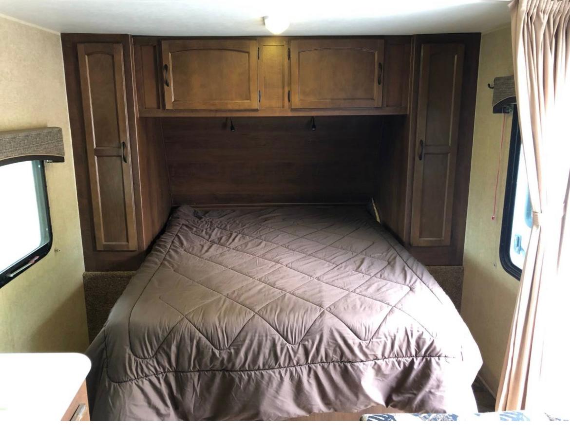 RV rental interior: Comfortable bedroom with a quilted brown comforter, wood cabinets, and windows on each side.. Jayco Jay Feather Ultra Lite 2014