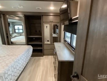 Spacious RV rental bedroom featuring a comfortable bed, mirrored dresser, and ample storage, perfect for your next adventure.. Grand Design Solitude 2022