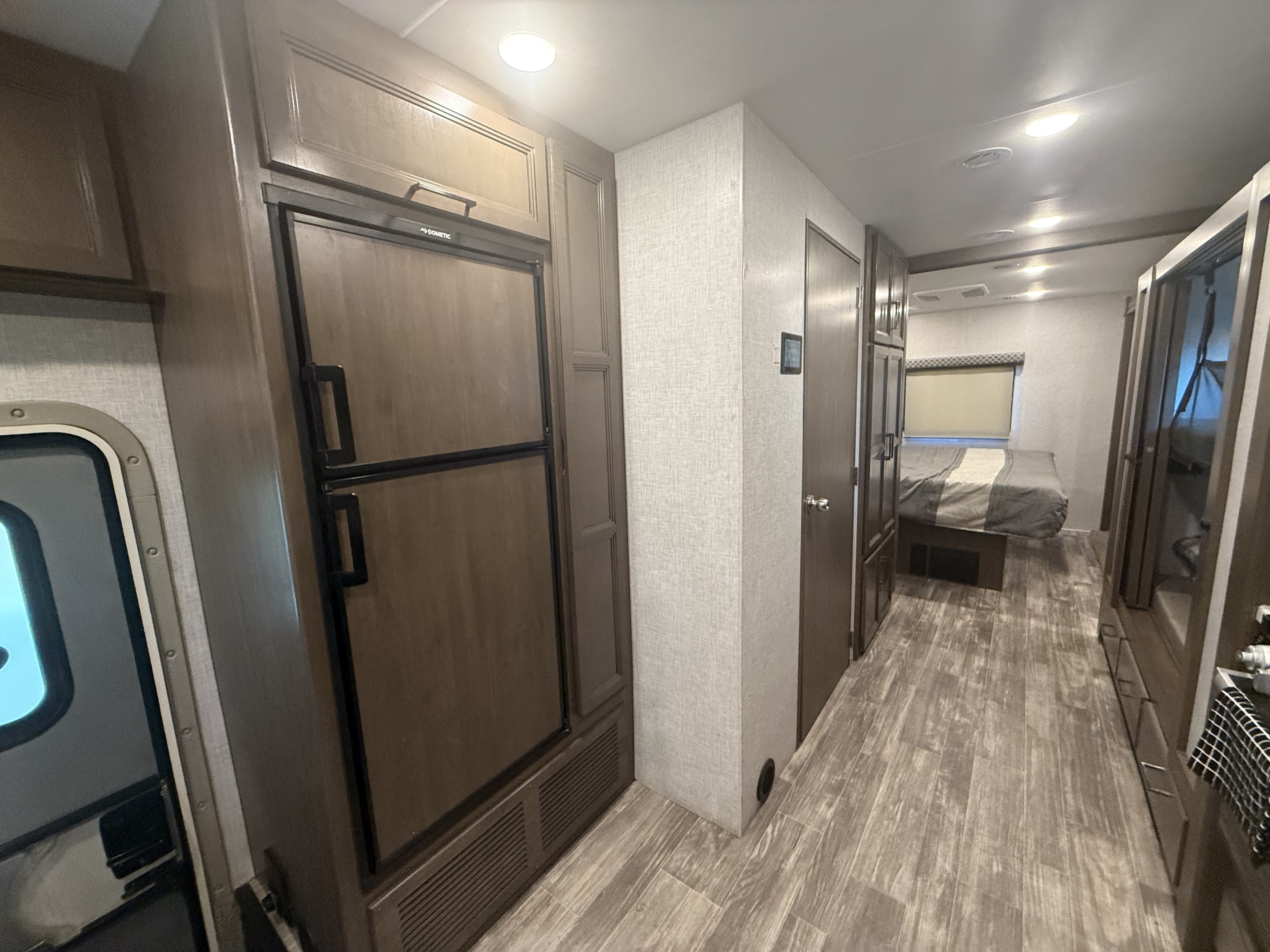 Explore this modern RV rental interior, featuring a sleek kitchenette with fridge/freezer and a hallway leading to a cozy bedroom.. Thor Hurricane 2022