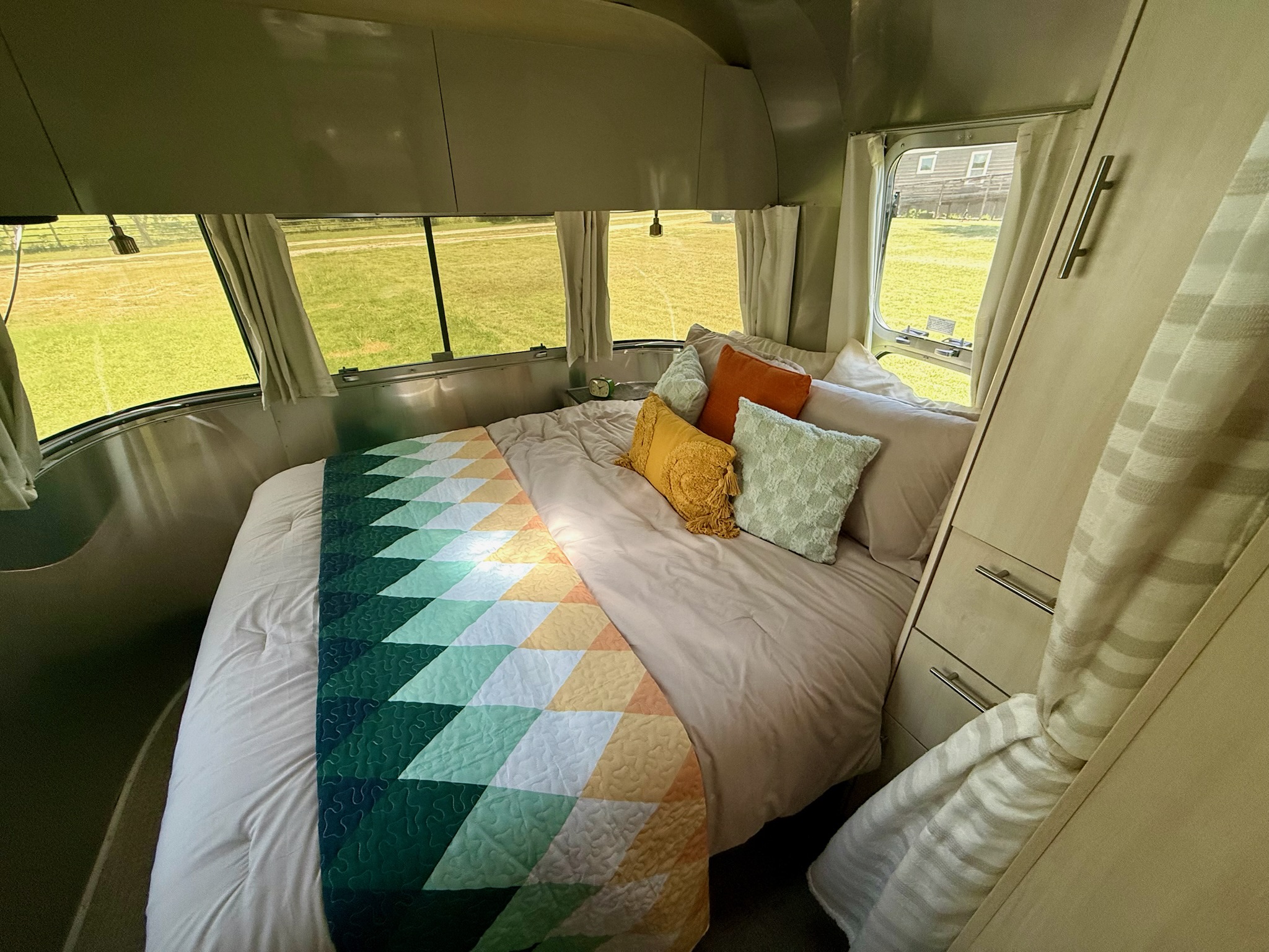 Cozy Airstream RV rental bedroom with colorful quilt, ample windows, and natural light for your next adventure.. Airstream Flying Cloud 2022