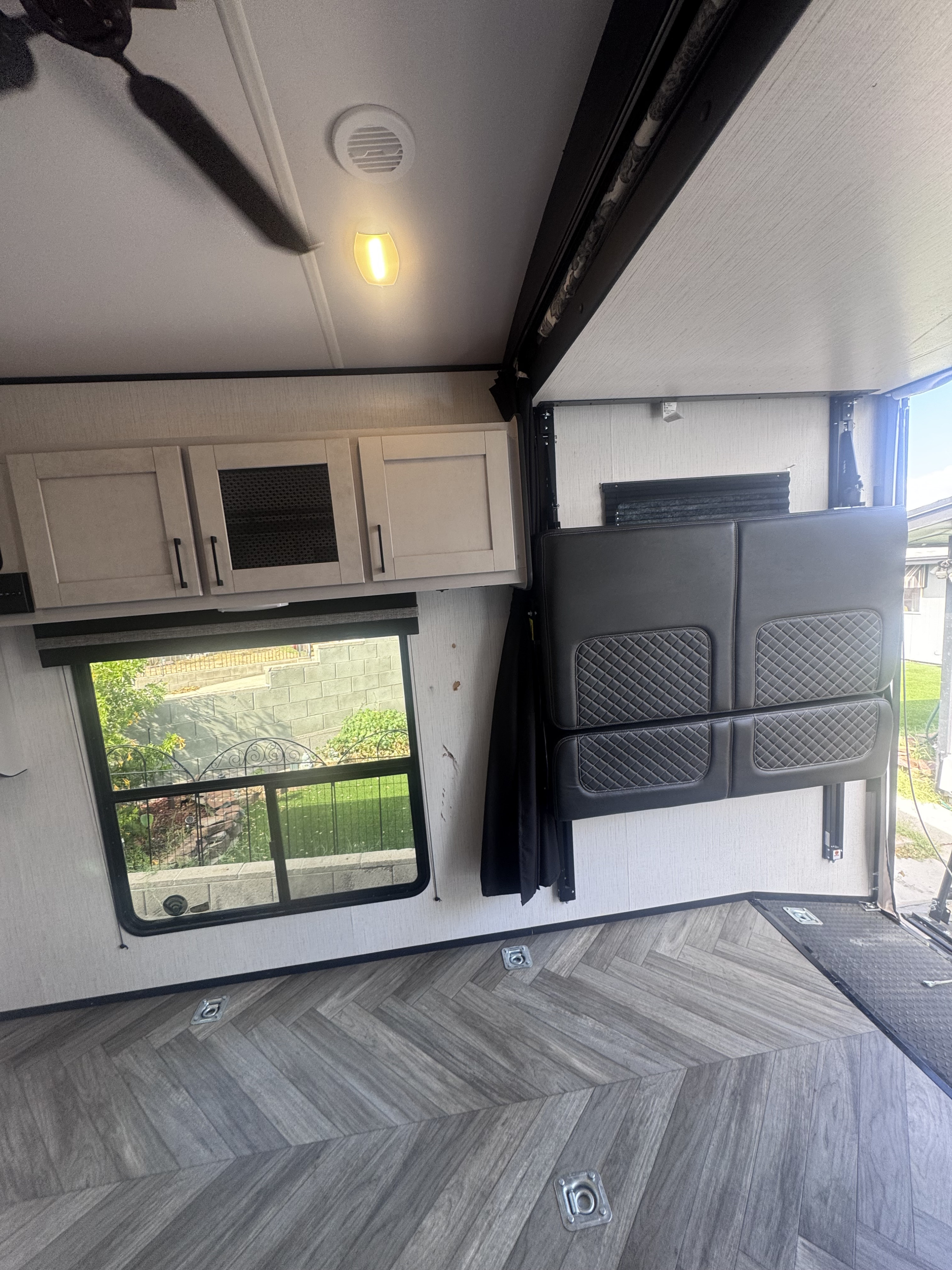 Inside an RV rental: herringbone floor, overhead cabinets, window, and versatile fold-down bunk seating.. Heartland Torque 2022