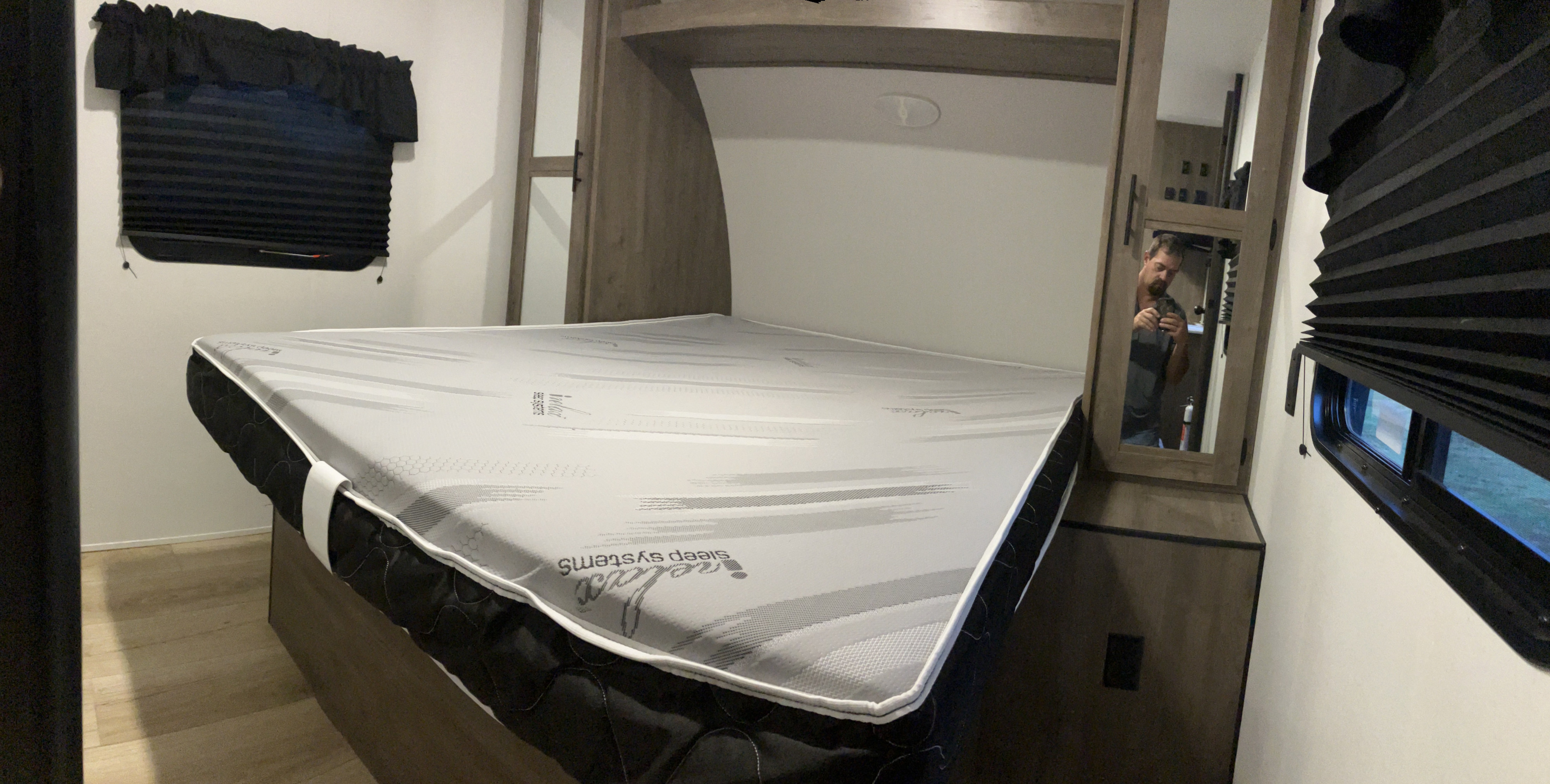Cozy RV rental bedroom featuring a Sleep Systems mattress, dark pleated blinds, and built-in storage. Ready for travel!. Heartland RVs Pioneer 2023