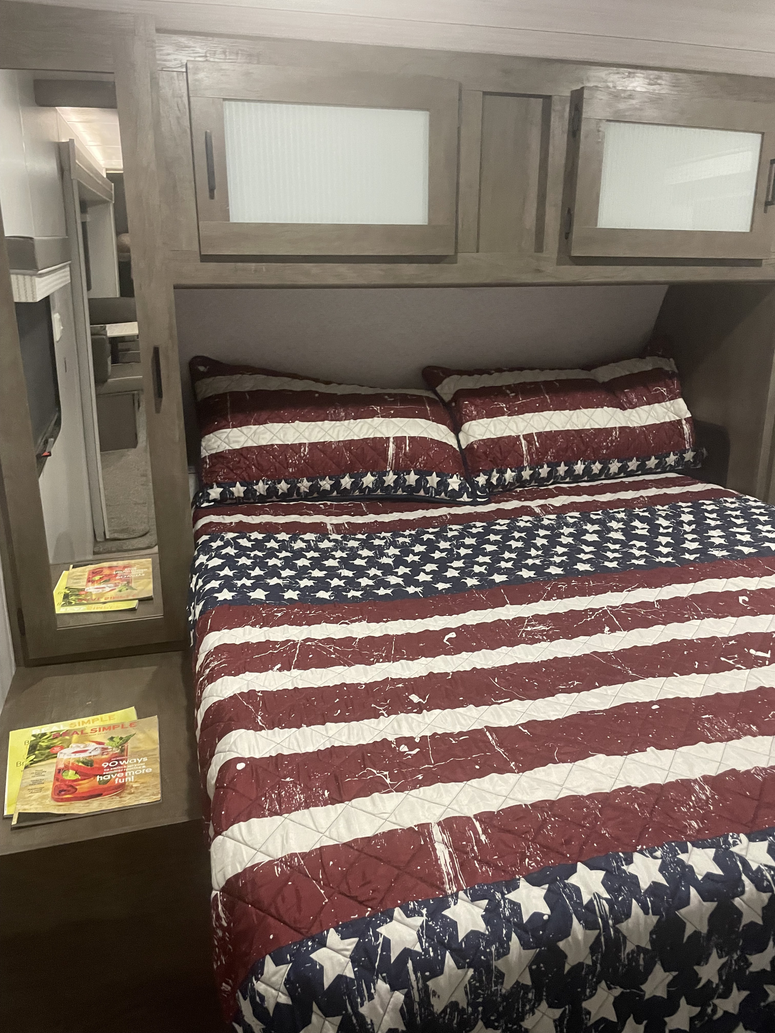 Sleep soundly in this RV rental's bedroom, featuring a patriotic quilt, storage, and a mirrored closet door.. Forest River Salem 2022