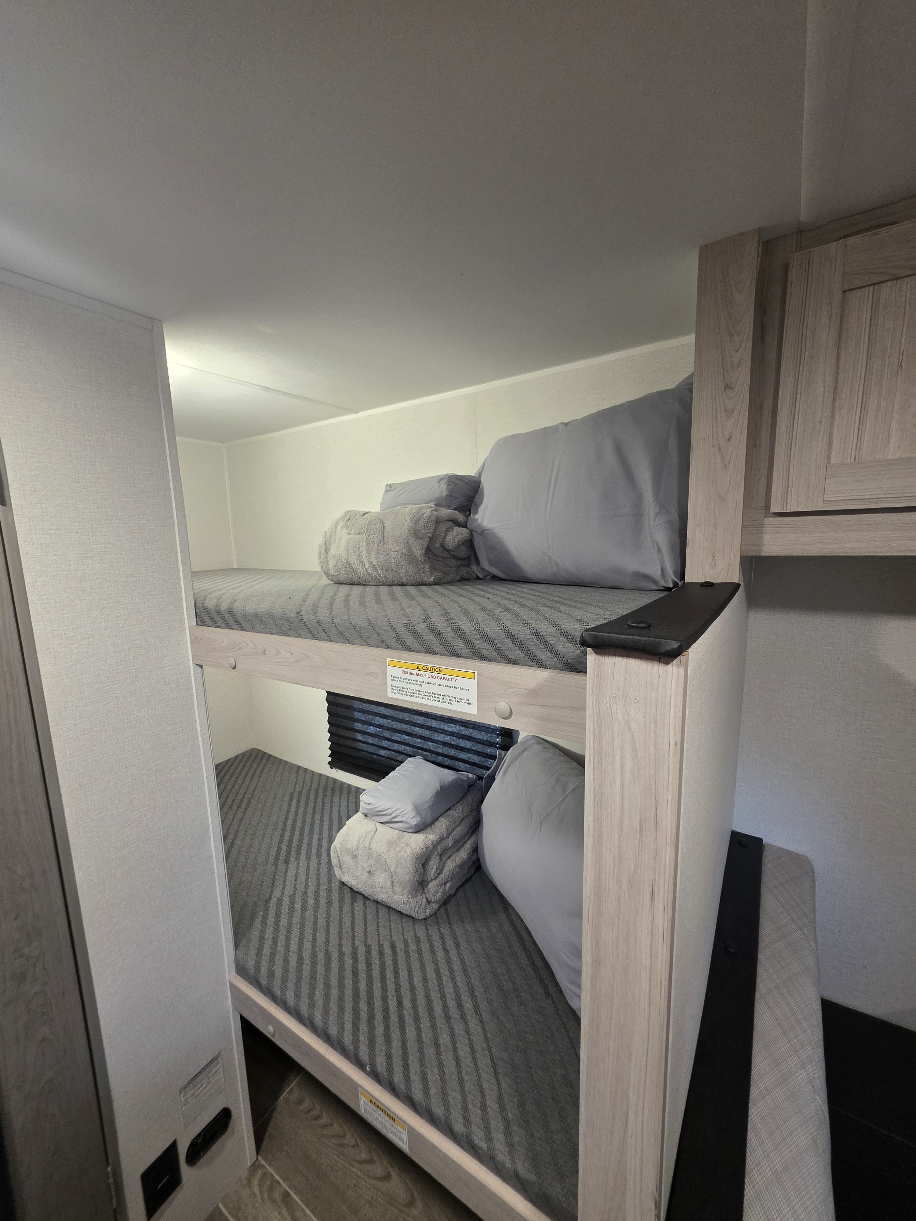 Comfortable rv rental bunk beds with pillows and blankets for a cozy camping trip in a travel trailer.. Heartland RVs Pioneer 2025