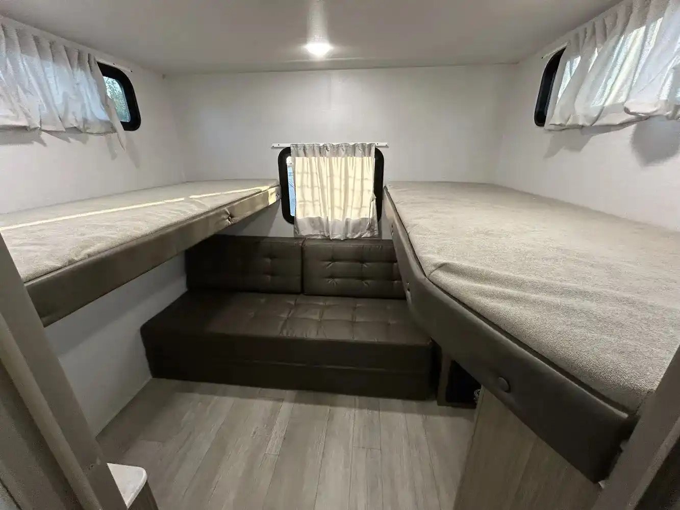 Inside this **rv rental**: A compact bunkhouse featuring foldable bunks and a sofa, ideal for flexible sleeping.. Forest River Wildwood X-Lite 2025