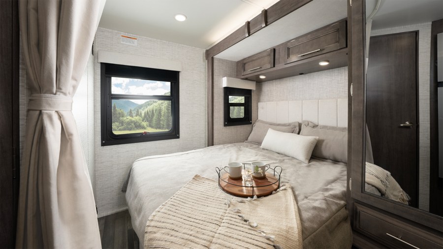 Cozy RV rental bedroom featuring a comfy bed, scenic mountain view from the window, and ample storage for a relaxing travel.. Entegra Coach Qwest SE 2025