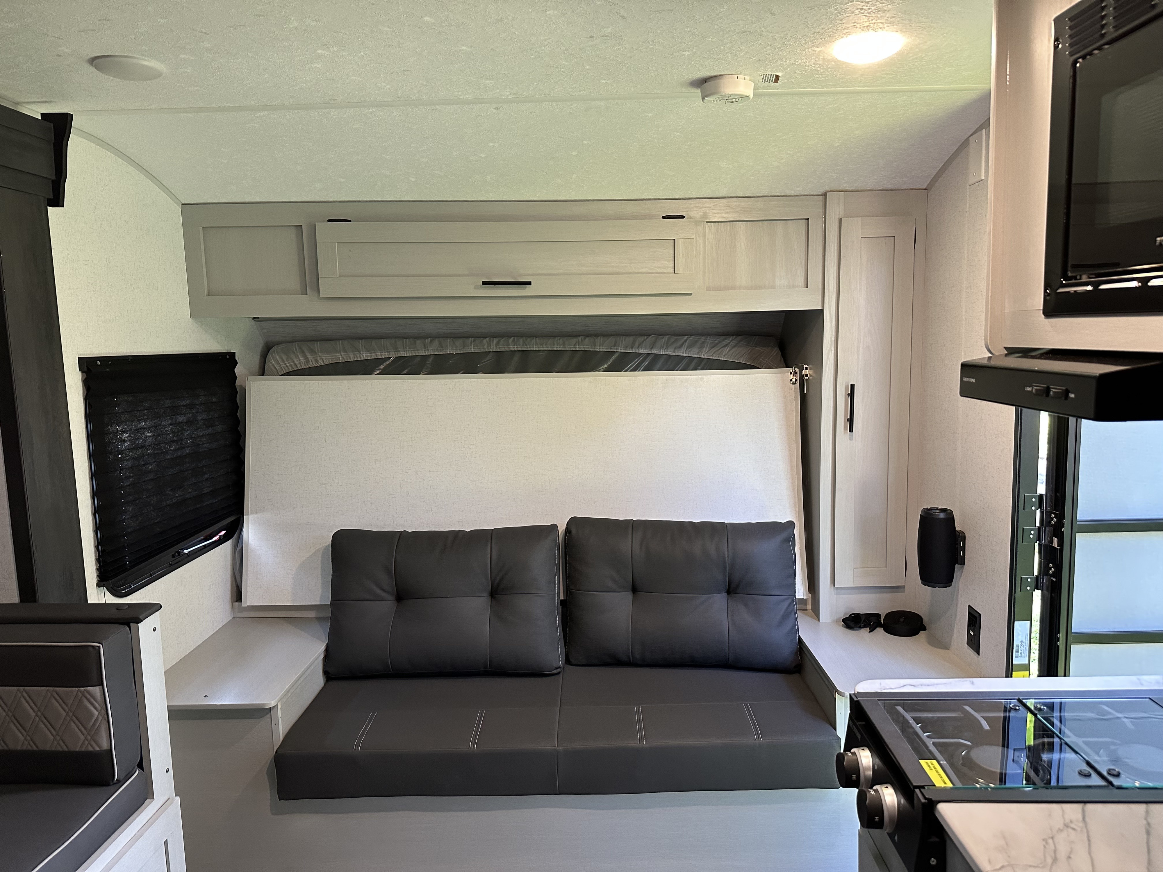 RV rental interior: A versatile space featuring a foldable bed above a comfy sofa, overhead cabinets, and a compact kitchen counter.. Forest River Salem FSX 2022