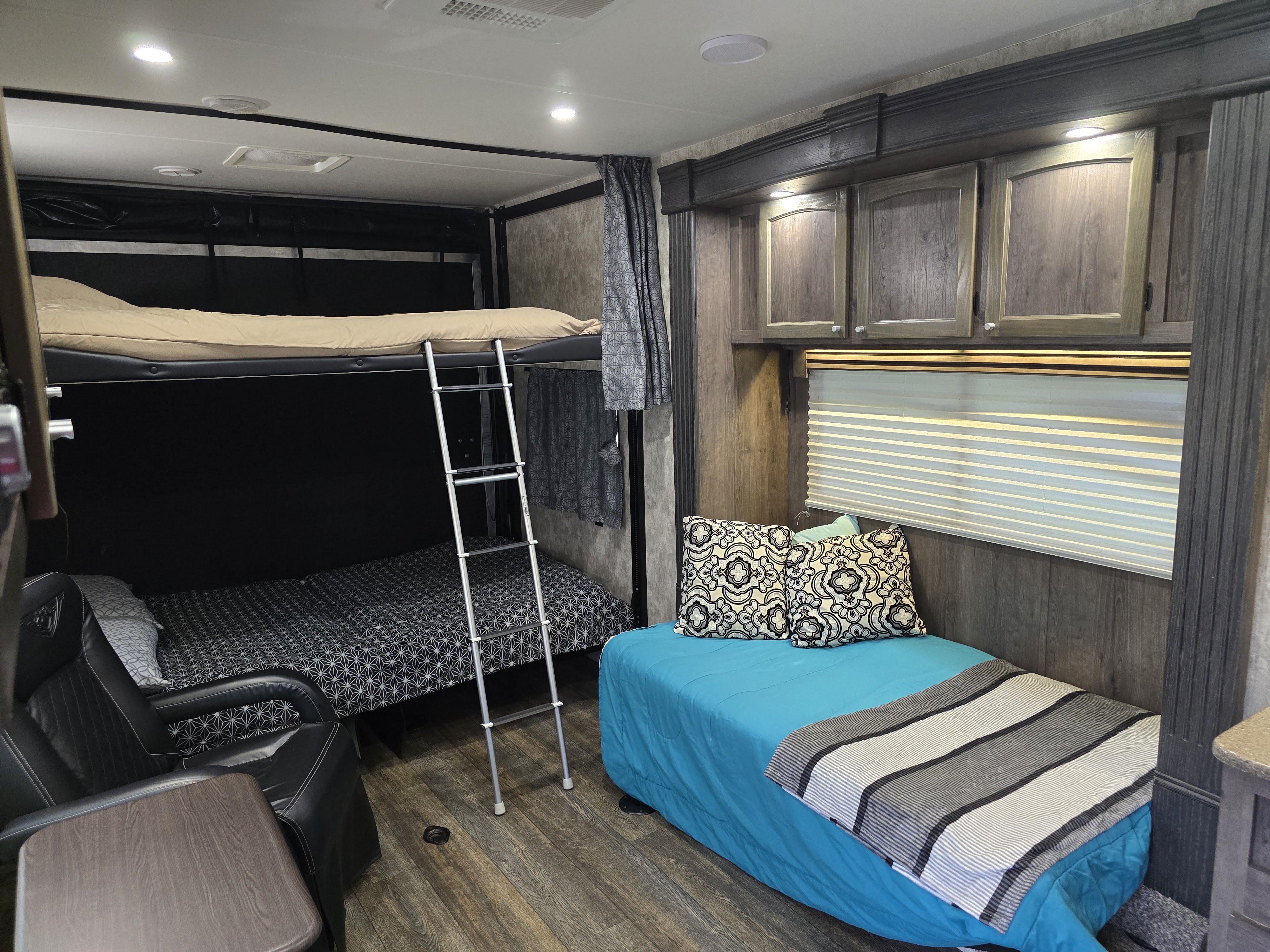 This inviting RV rental interior features comfortable bunk beds, a plush daybed with pillows, and an armchair, offering a cozy living space.. Eclipse Recreational Vehicles Attitude 2019