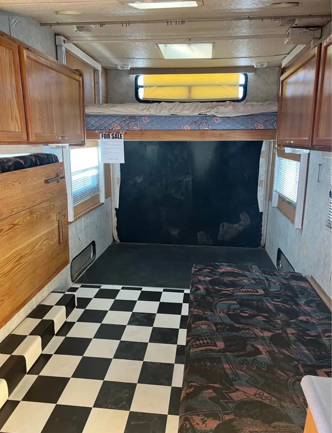 RV rental interior features an upper bunk bed, black and white checkered floor, and a toy hauler garage area.. Forest River Salem 2000
