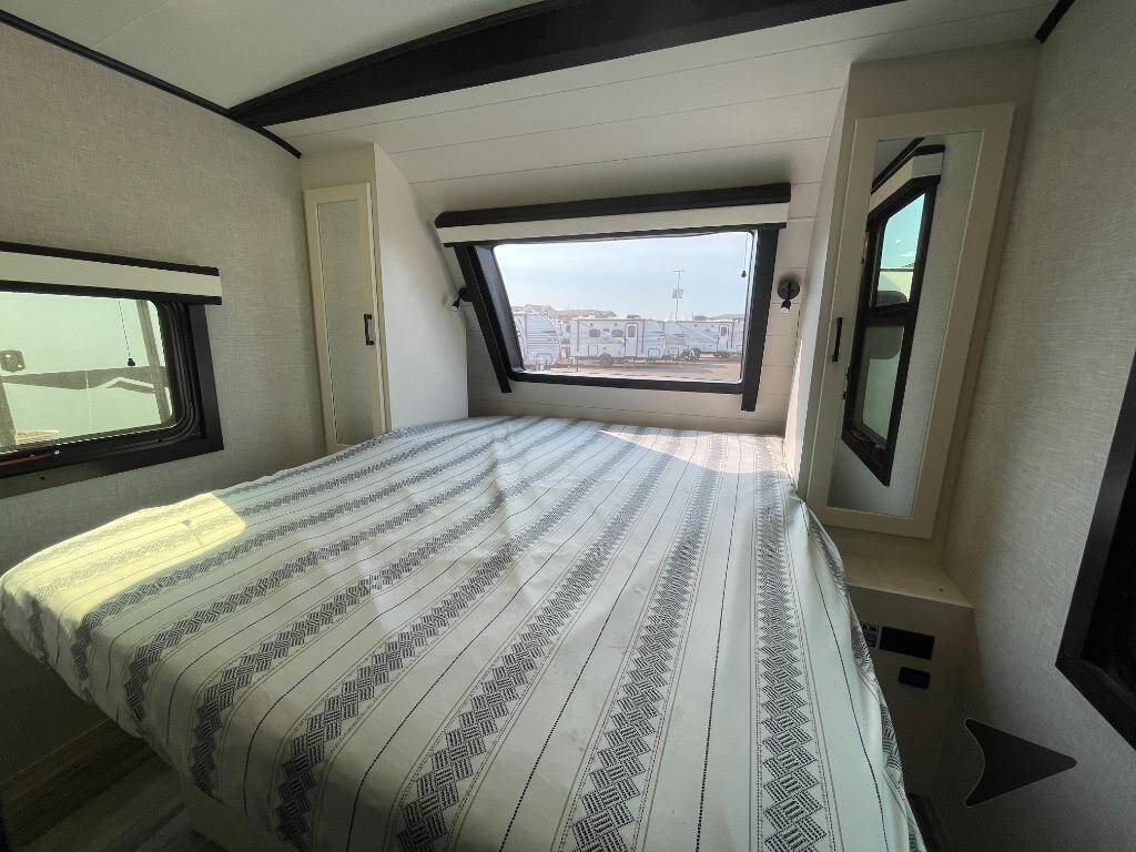 Spacious RV rental bedroom featuring a large bed, multiple windows, and built-in storage, ideal for comfortable travel.. Jayco White Hawk 2024