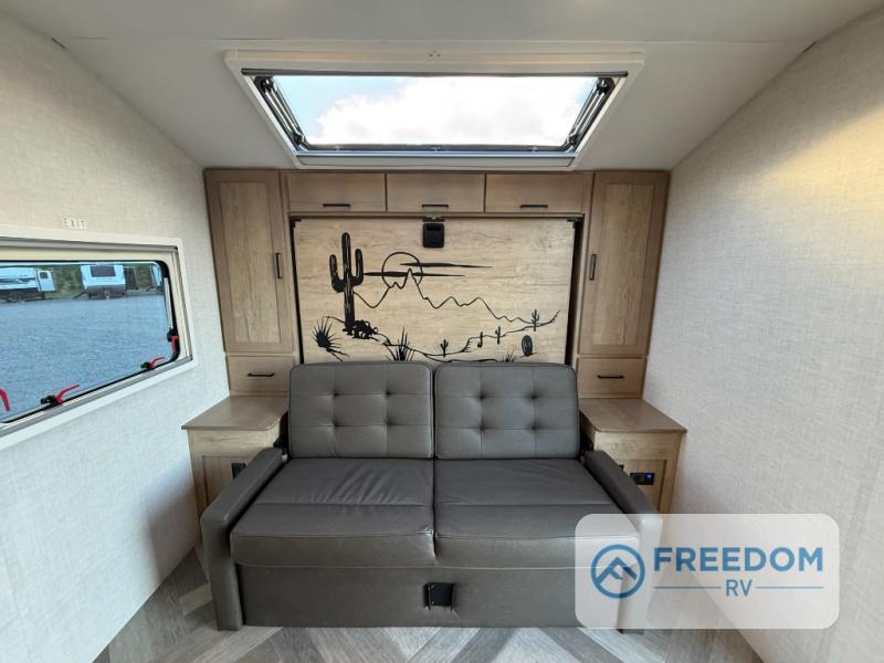 Cozy RV rental interior featuring a gray sofa bed, desert mural, and bright skylight. Ideal for comfortable travel and adventures.. Ember OVERLAND / 221MSL 2026