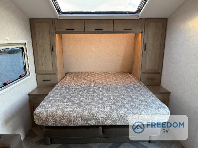 Cozy RV rental bedroom with a comfortable bed, overhead cabinets, and a window for natural light.. Ember OVERLAND / 221MSL 2026