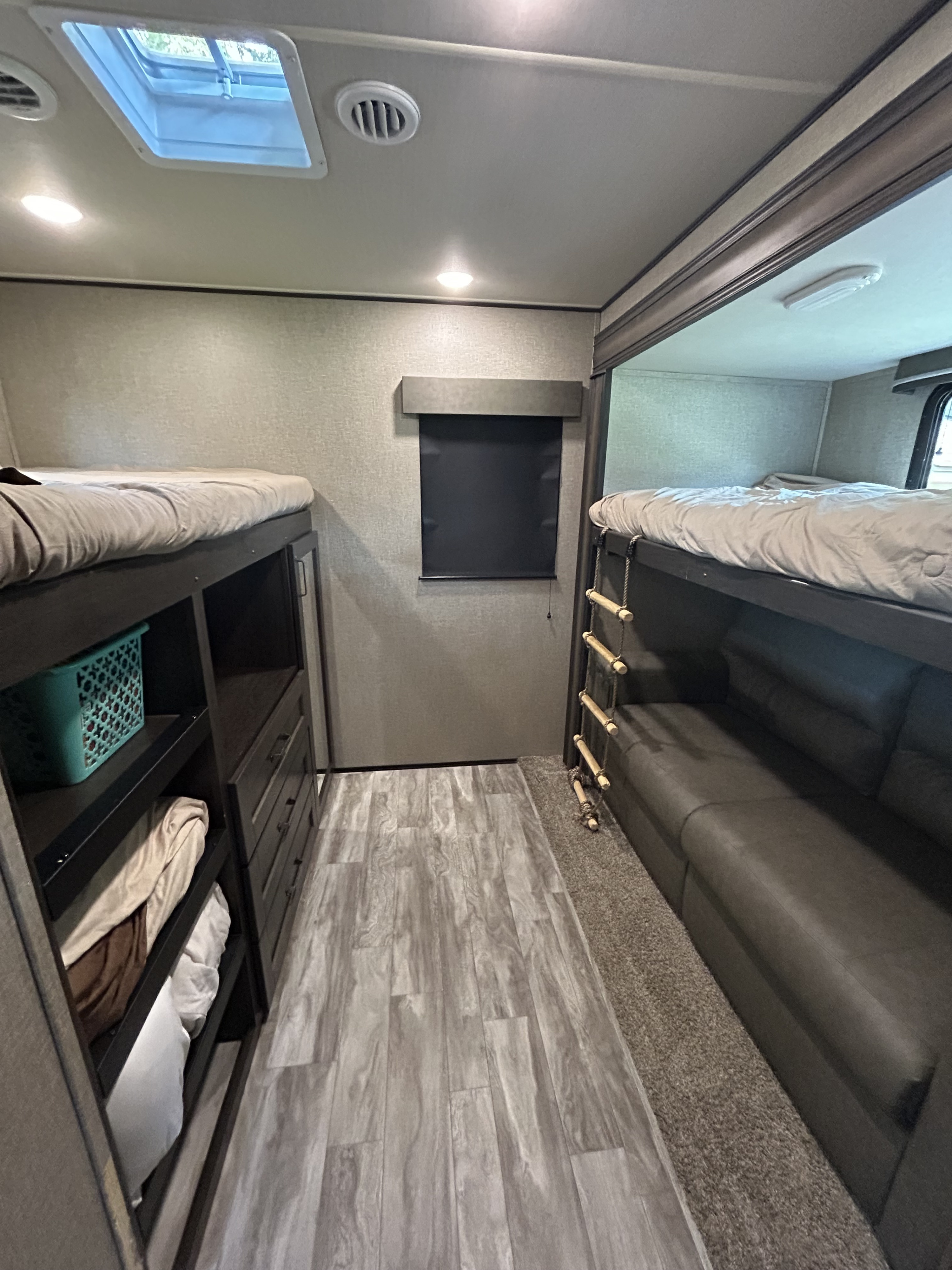 Cozy RV rental interior showing bunk beds, integrated storage, sofa sleeper, and skylight for comfortable travel.. Grand Design Reflection 2021