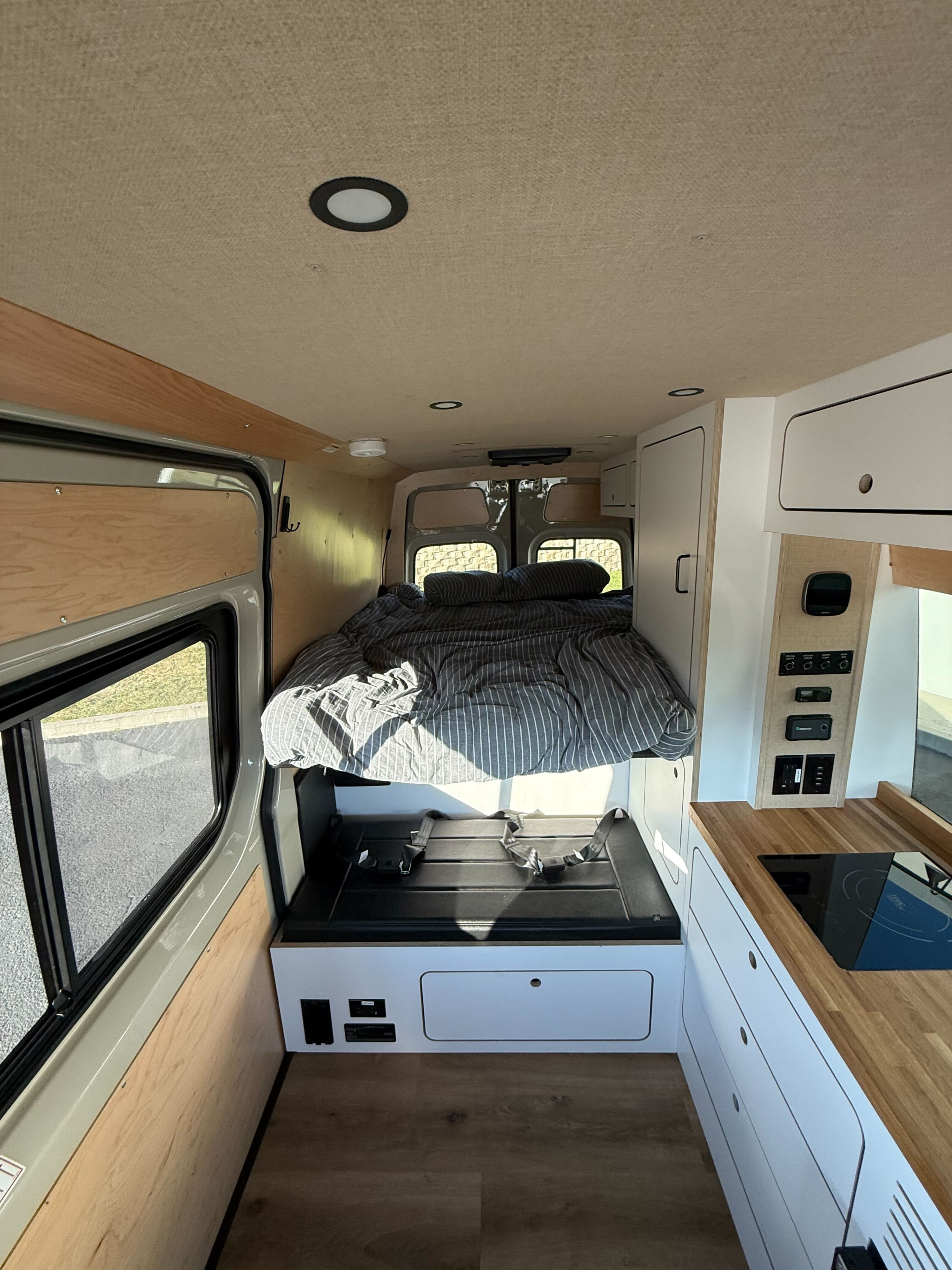Inside a modern **rv rental**: a comfy bed, functional kitchenette, and control panel for ultimate road trip comfort.. Mercedes-Benz Sprinter RV Motorhome Campervan 2025