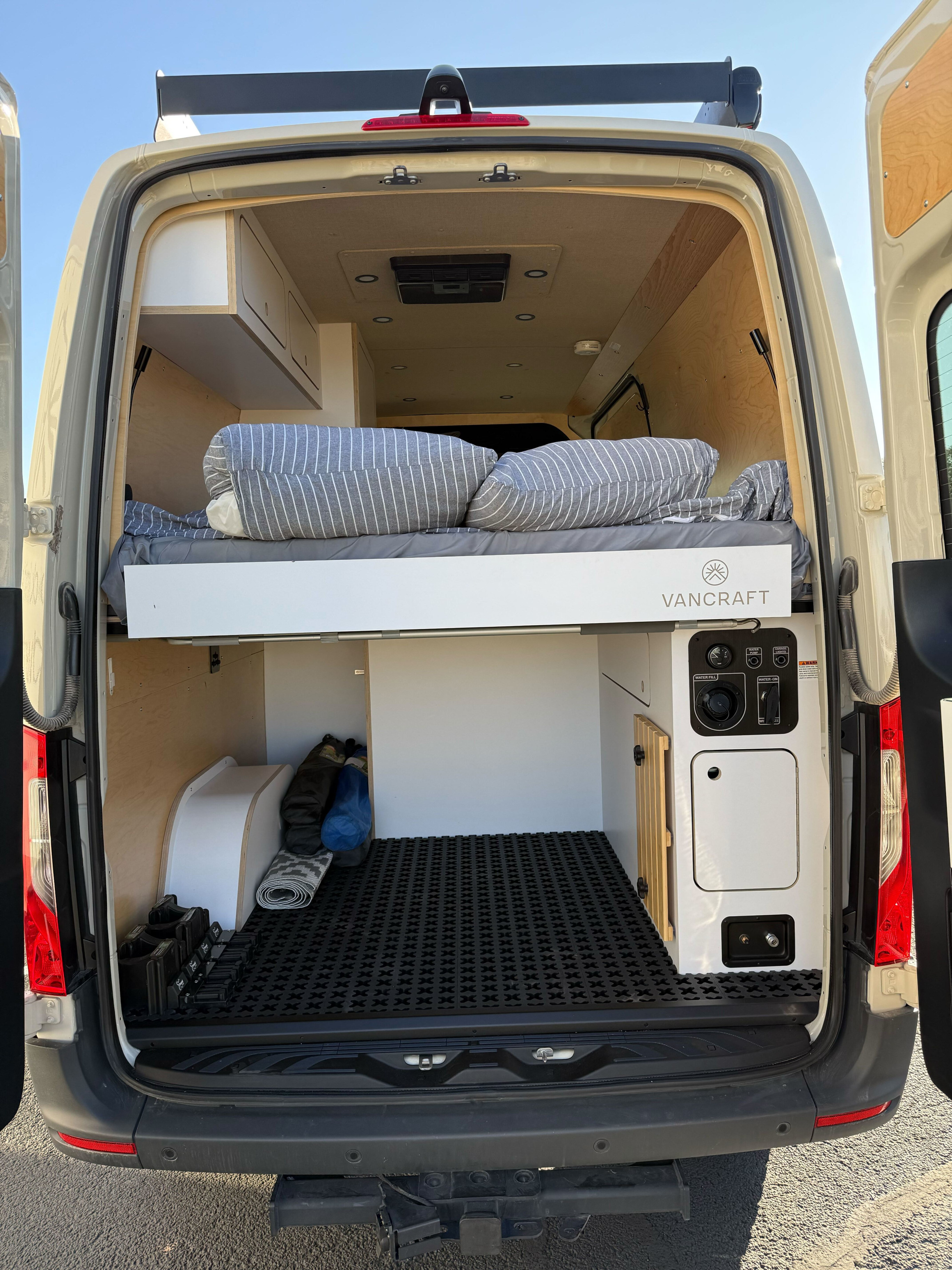 Inside a Vancraft RV rental: rear view with cozy bed, ample storage, and utility controls for your next adventure.. Mercedes-Benz Sprinter RV Motorhome Campervan 2025