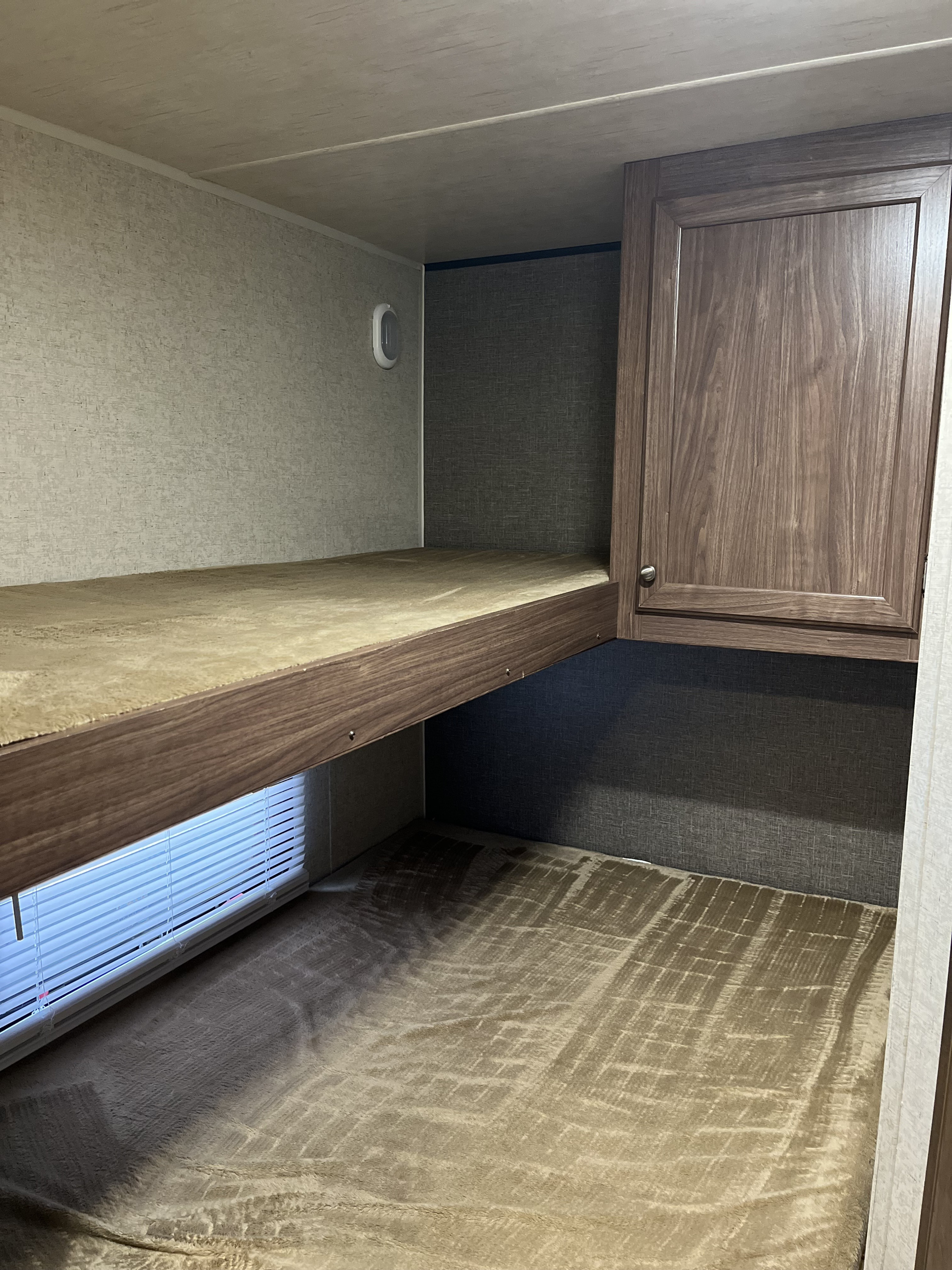 Cozy RV rental interior with bunk beds, a window, and convenient cabinet storage, perfect for family travel.. Heartland RVs Pioneer 2018
