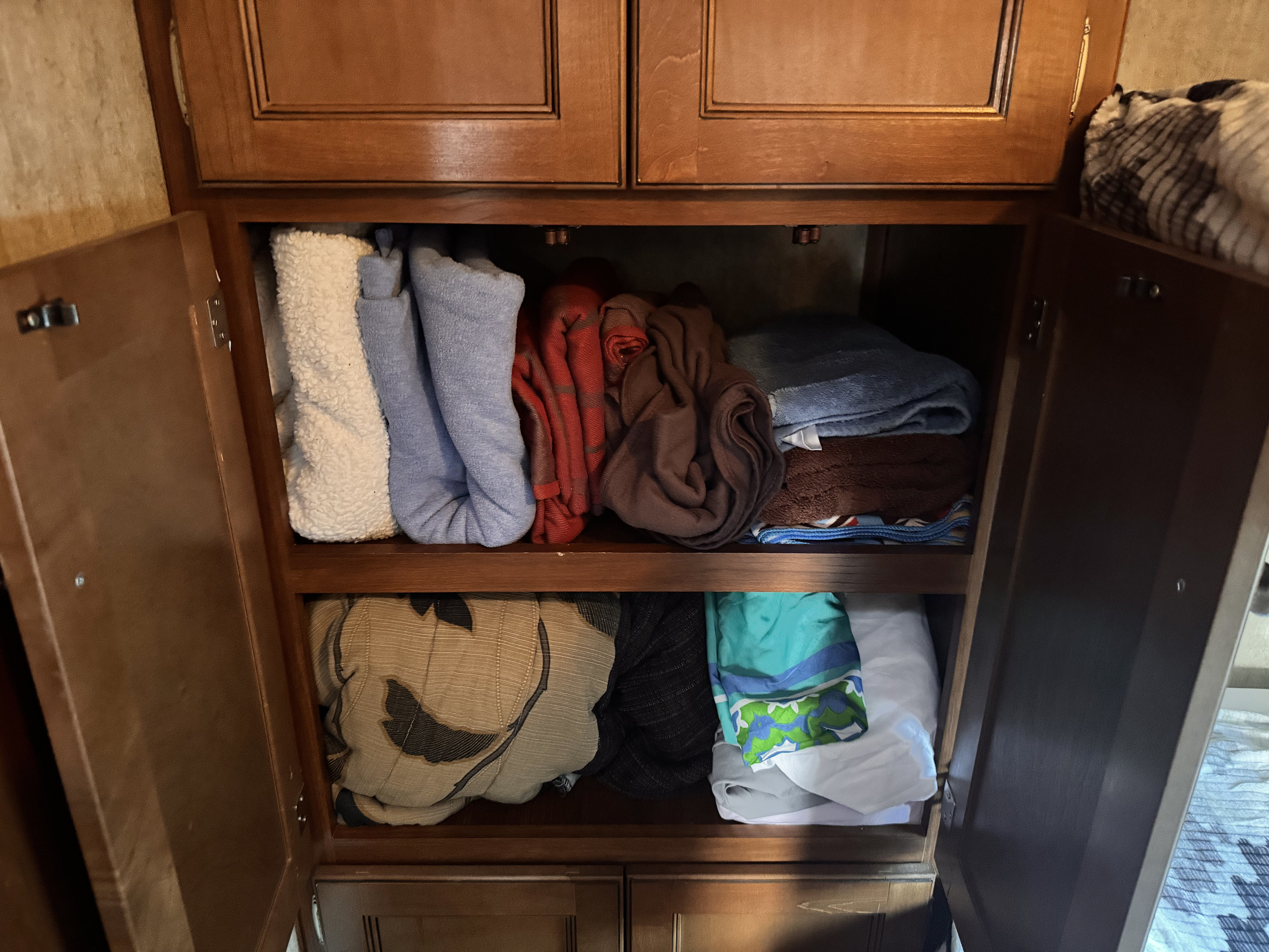 RV rental storage: Organized cabinet with neatly folded towels, blankets, and linens.. Keystone RV Bullet Ultra Lite 2014