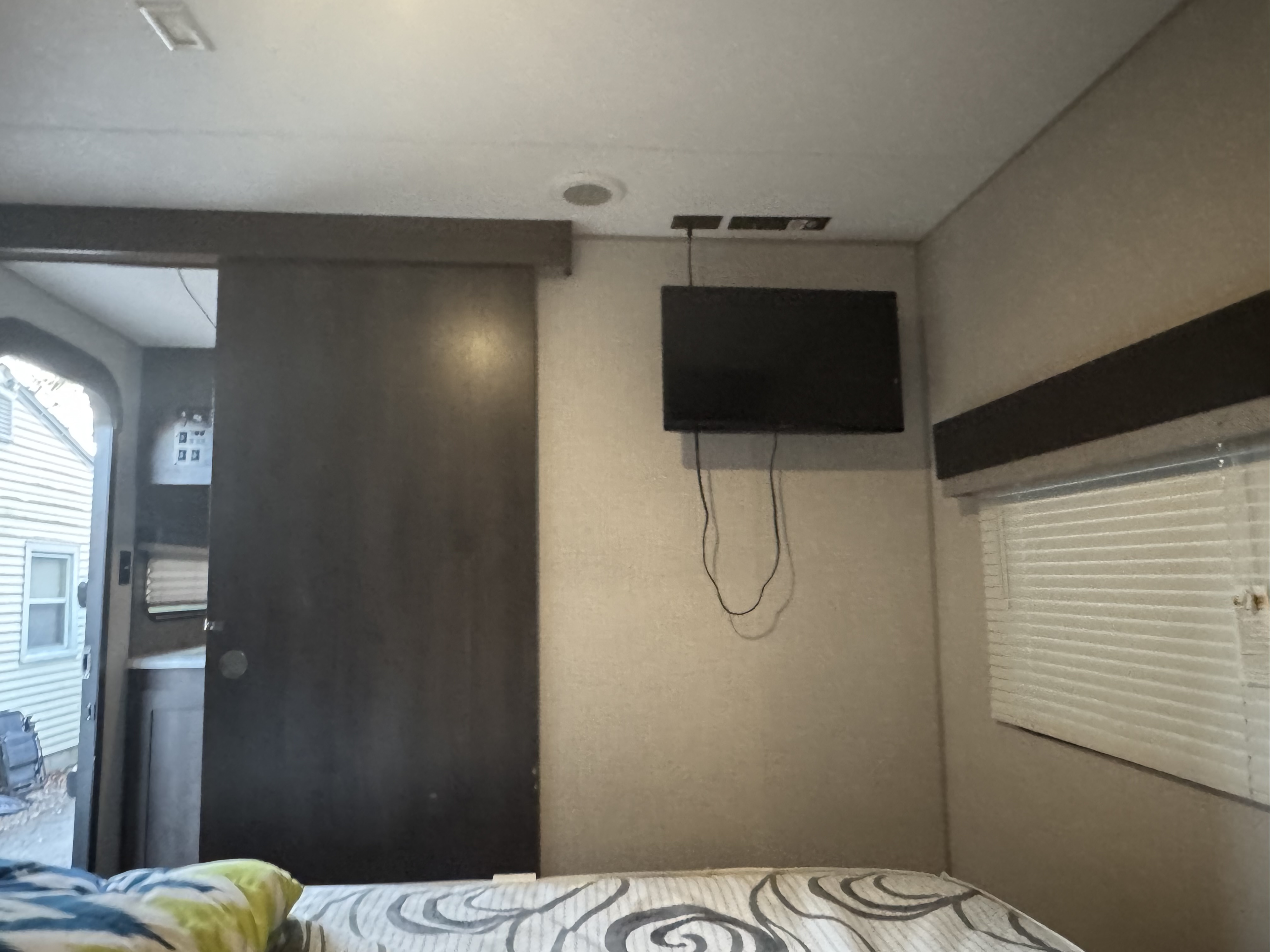 Cozy RV rental bedroom featuring a mounted TV, window with blinds, and a sliding door.. Sportsmen Classic 2020