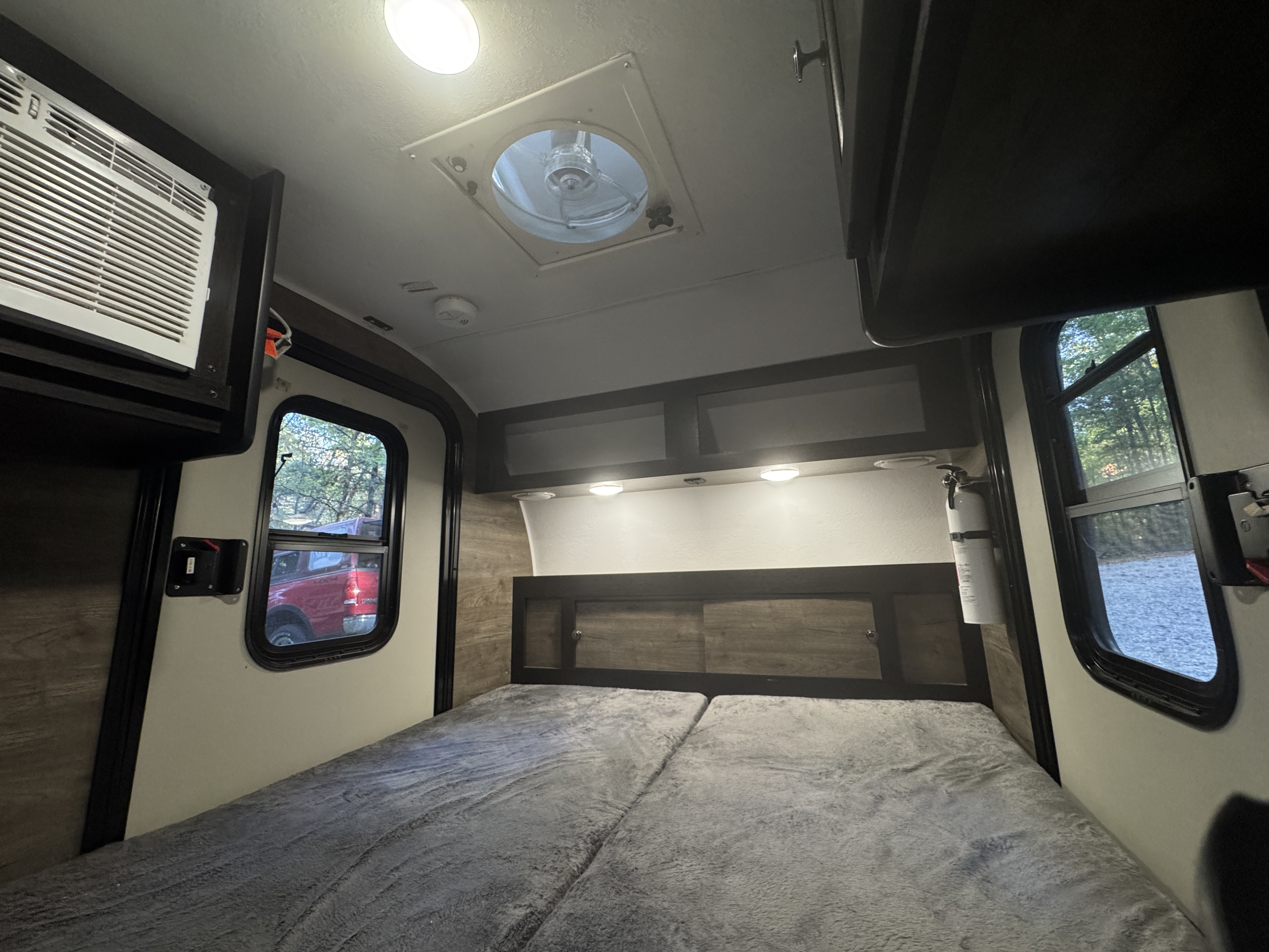 Cozy RV rental bedroom with a comfy bed, overhead AC, ceiling vent, and windows offering views of the outdoors.. Braxton Creek Bushwhacker 2022